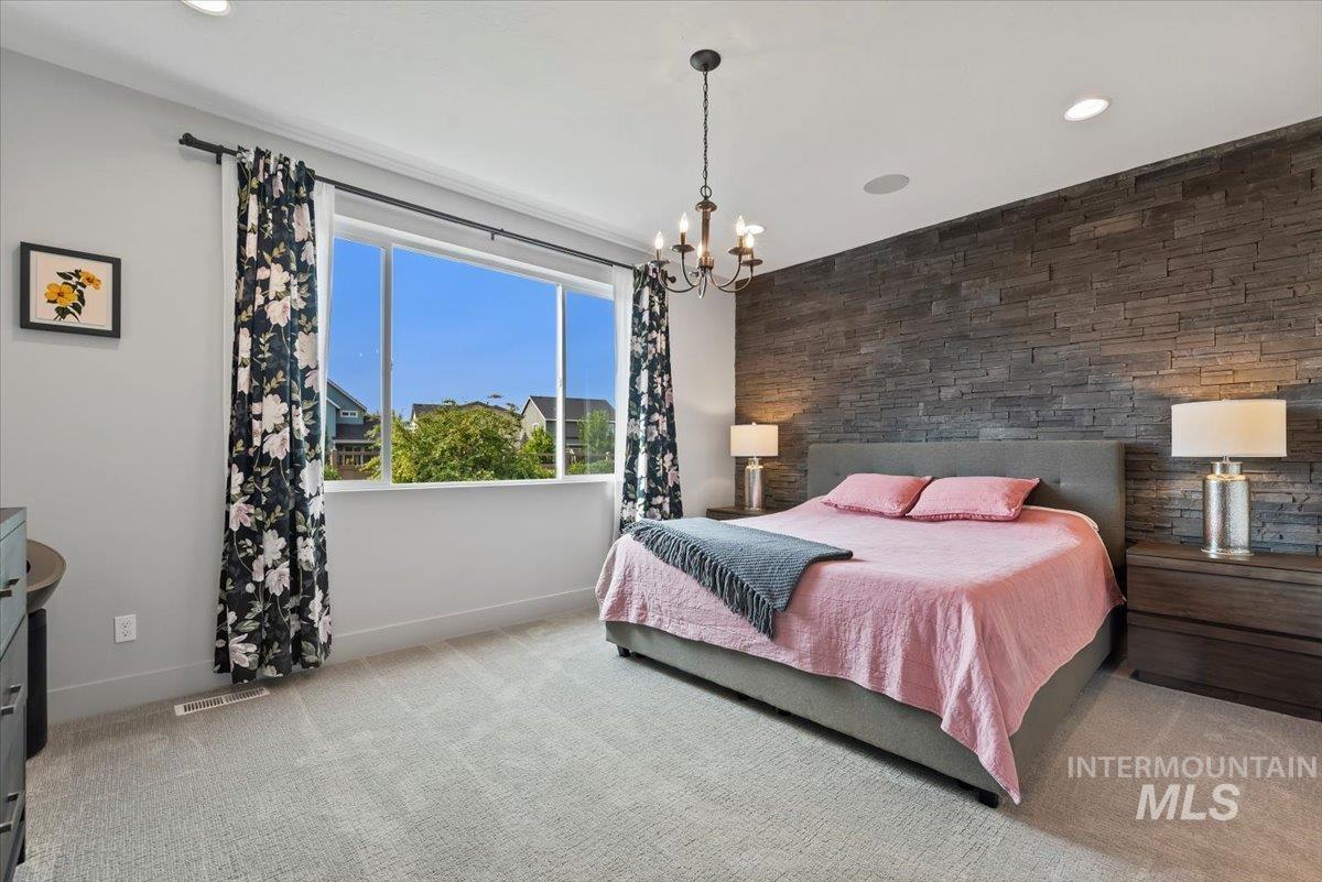 Bedroom featuring light carpet, a chandelier, recessed lighting, and an accent wall