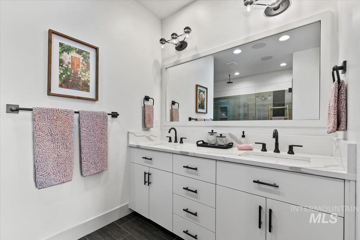 Bathroom featuring a stall shower, double vanity, and recessed lighting