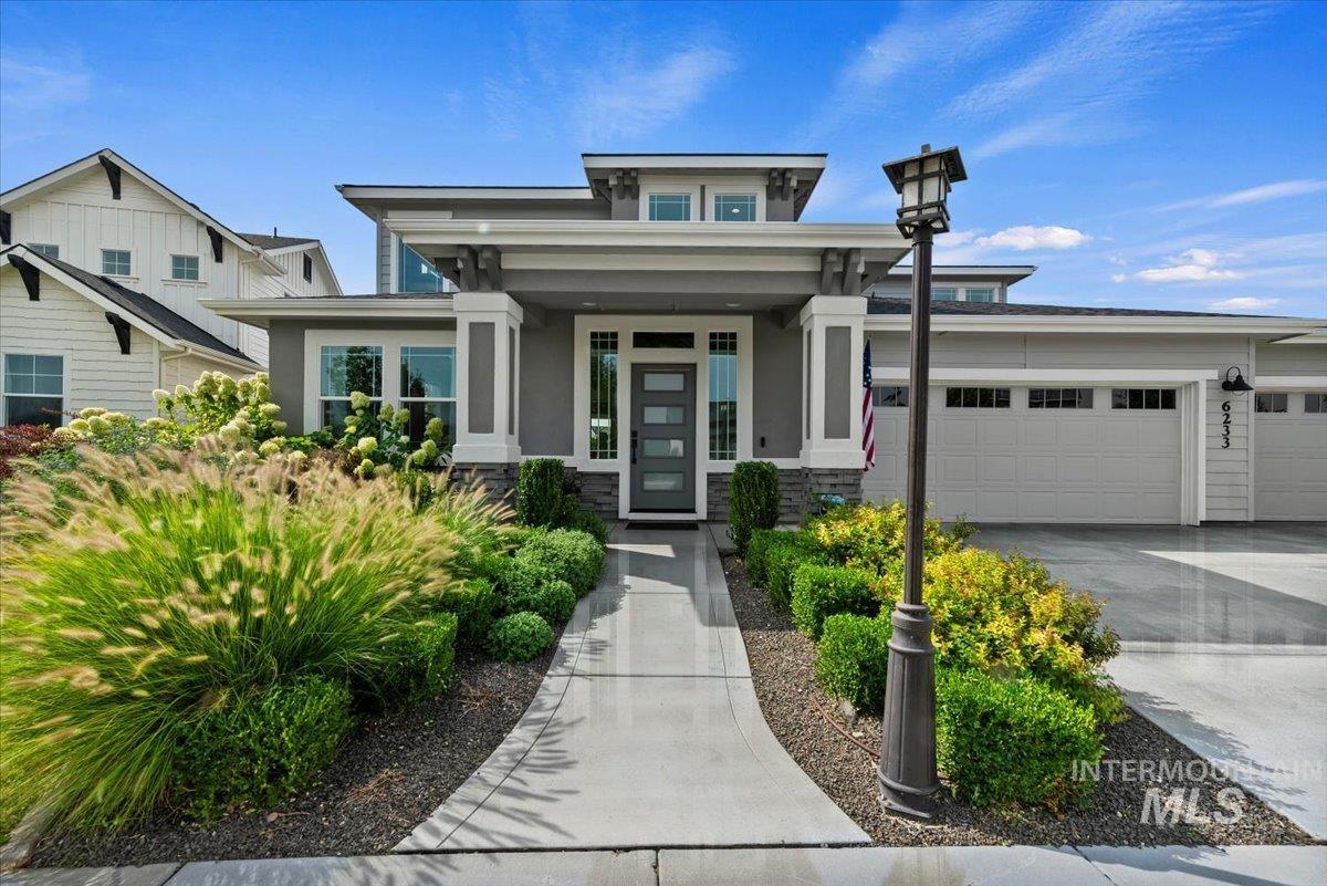 View of front of house with stucco siding, concrete driveway, an attached garage, and covered porch