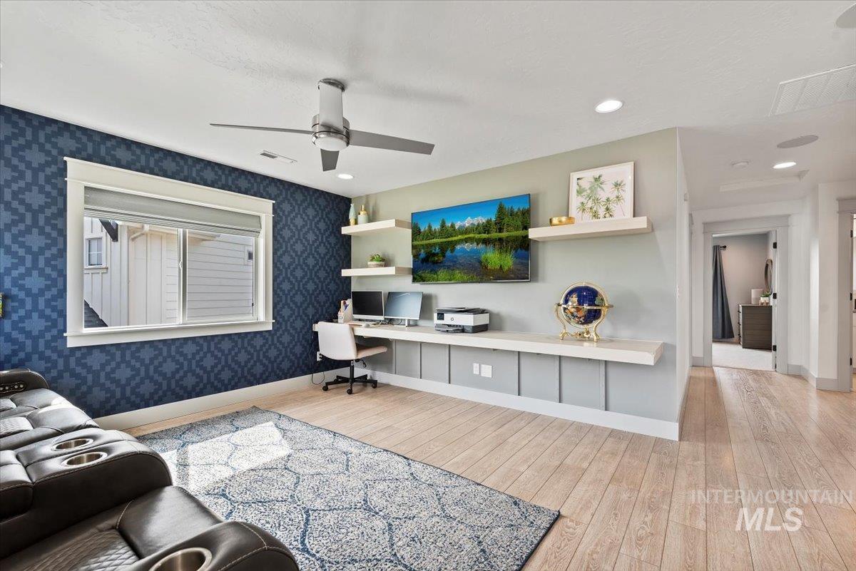 Living room featuring light wood-style floors, built in desk, ceiling fan, recessed lighting, and a textured ceiling