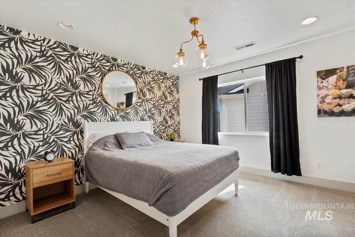 Carpeted bedroom featuring recessed lighting and a chandelier