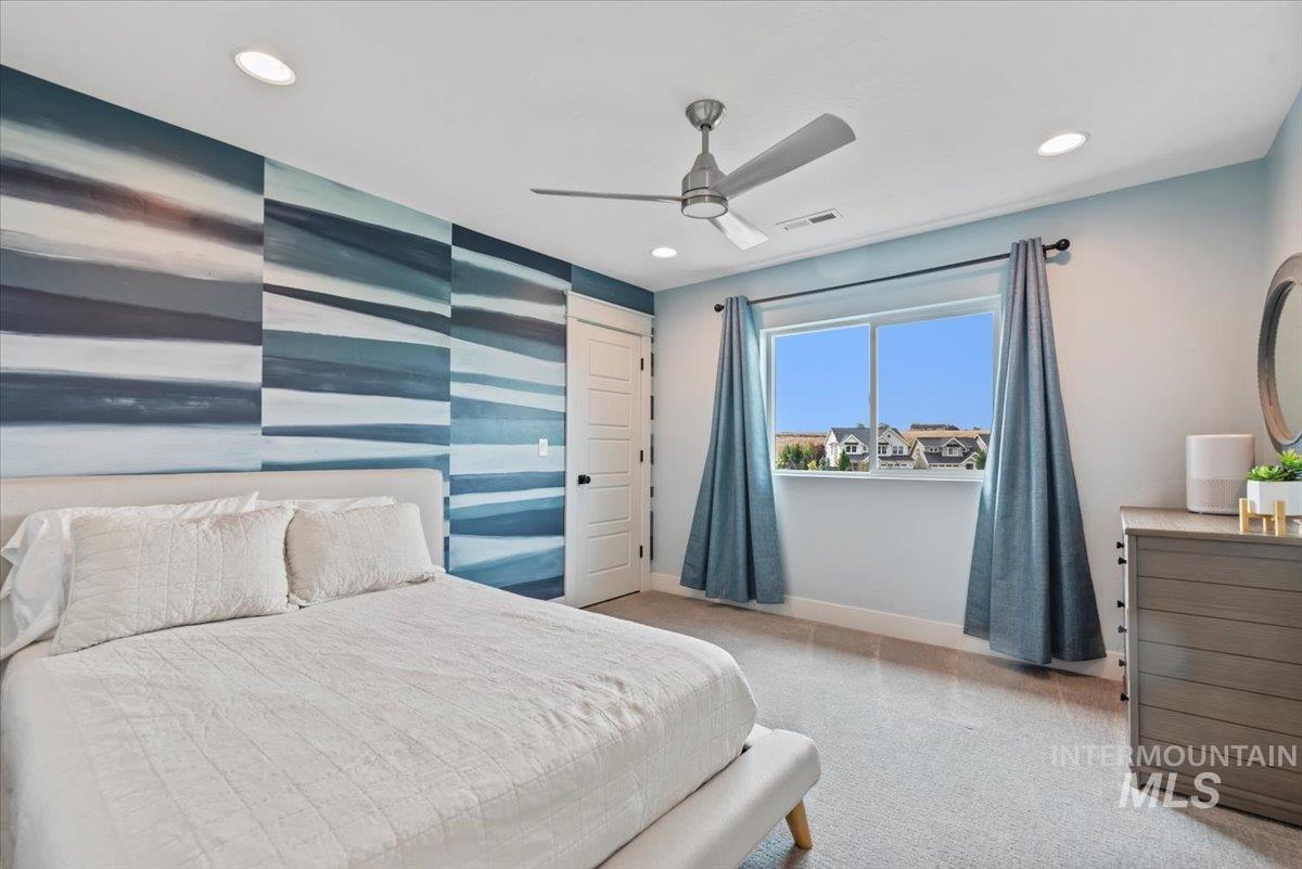 Bedroom with light colored carpet, a ceiling fan, recessed lighting, and an accent wall