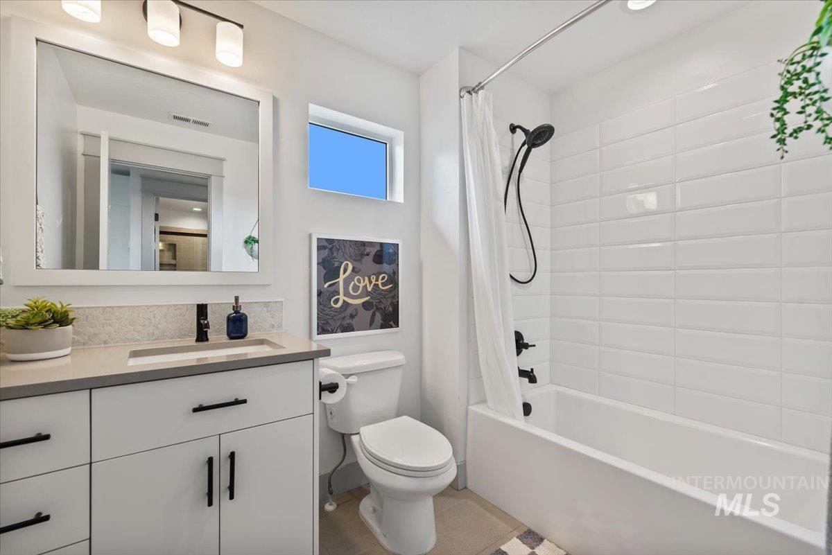 Full bath featuring shower / bath combo with shower curtain, vanity, and light tile patterned flooring