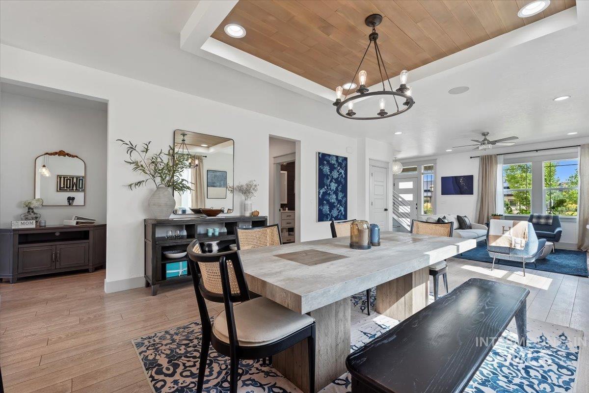 Dining space featuring a tray ceiling, ceiling fan, wood ceiling, light wood-style floors, and recessed lighting