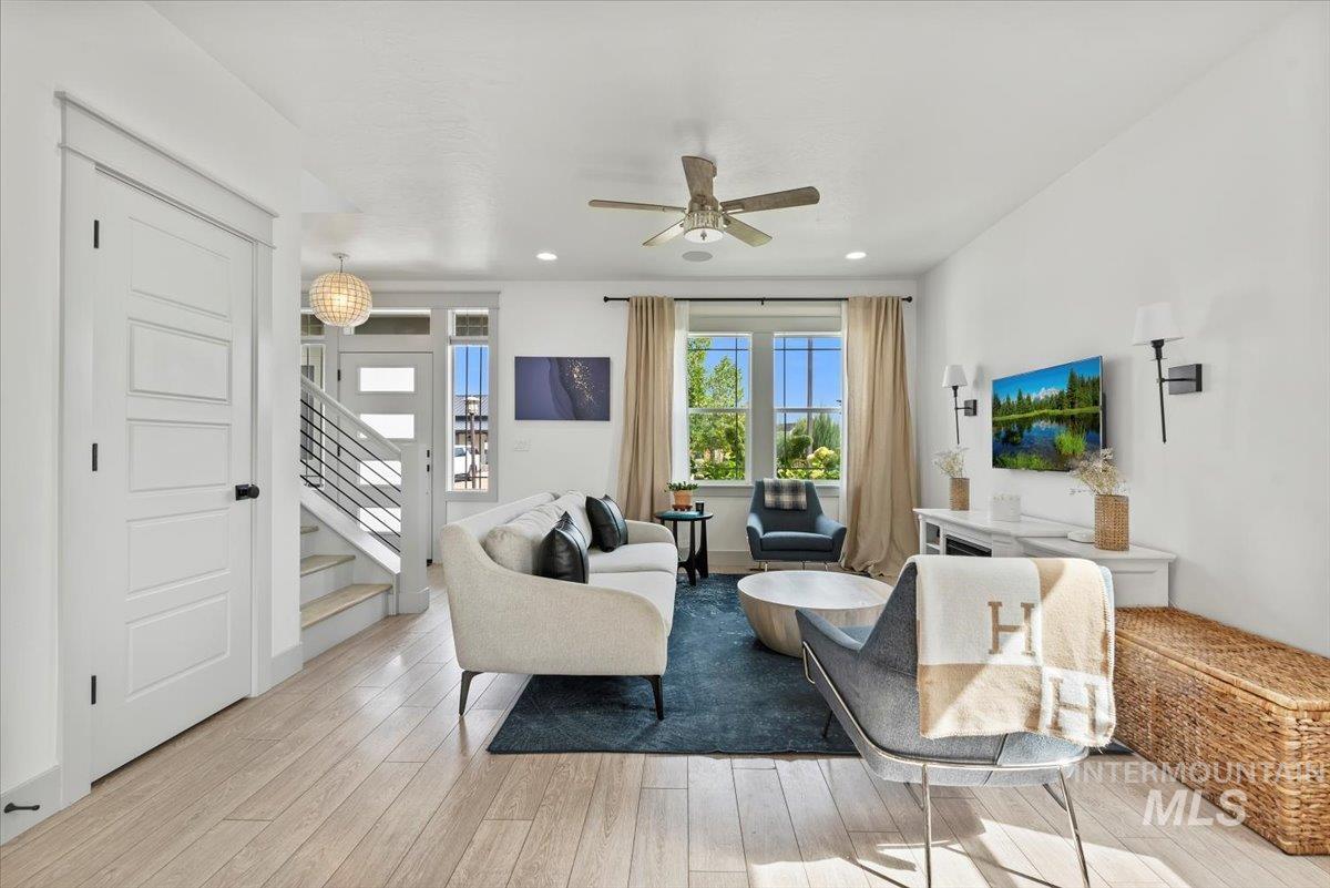 Living area with light wood-style floors, stairs, ceiling fan, and recessed lighting