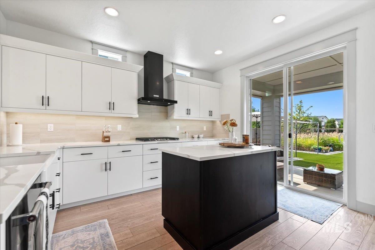 Kitchen featuring healthy amount of natural light, white cabinets, a center island, and recessed lighting