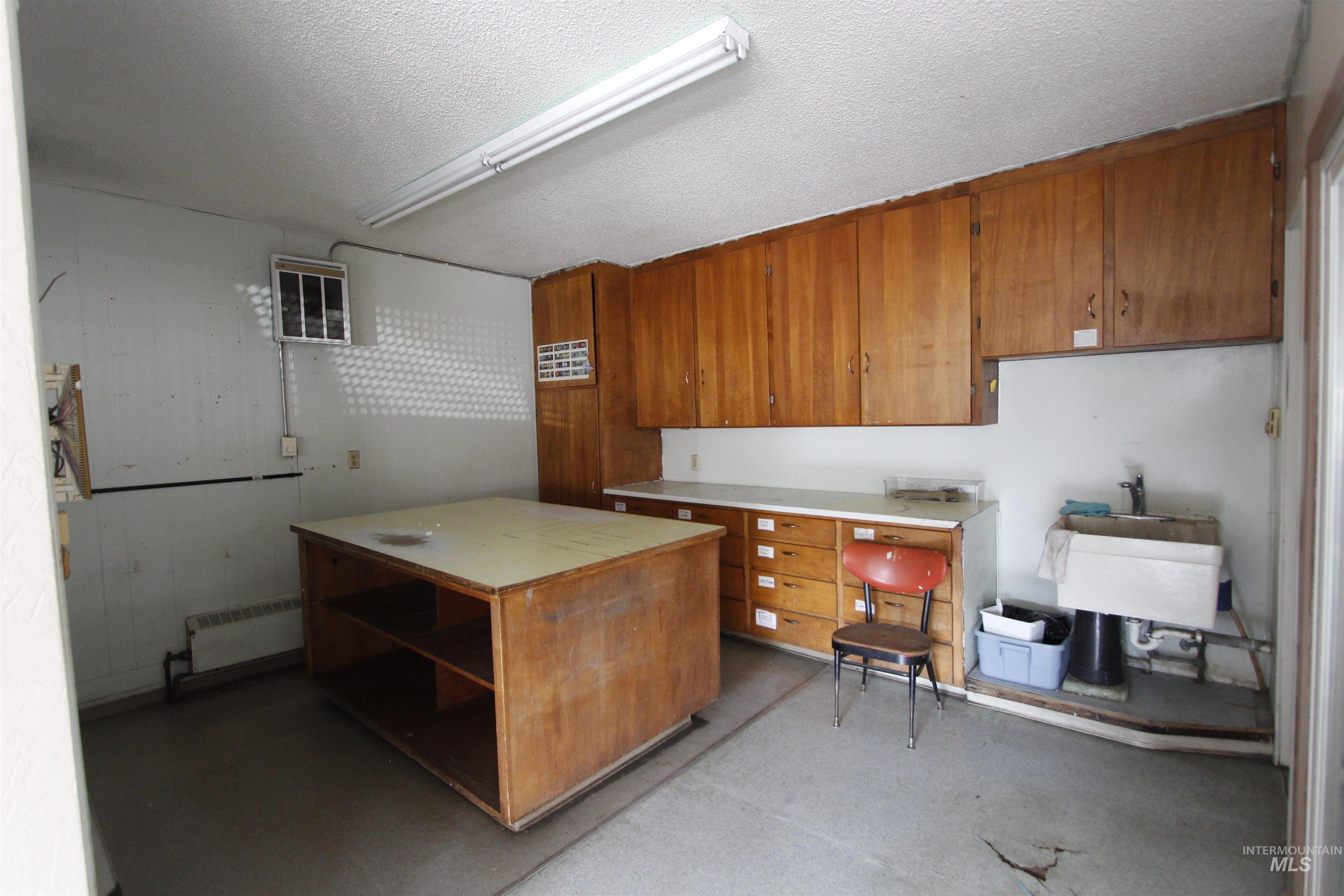 Kitchen featuring brown cabinets, a textured ceiling, light countertops, open shelves, and radiator