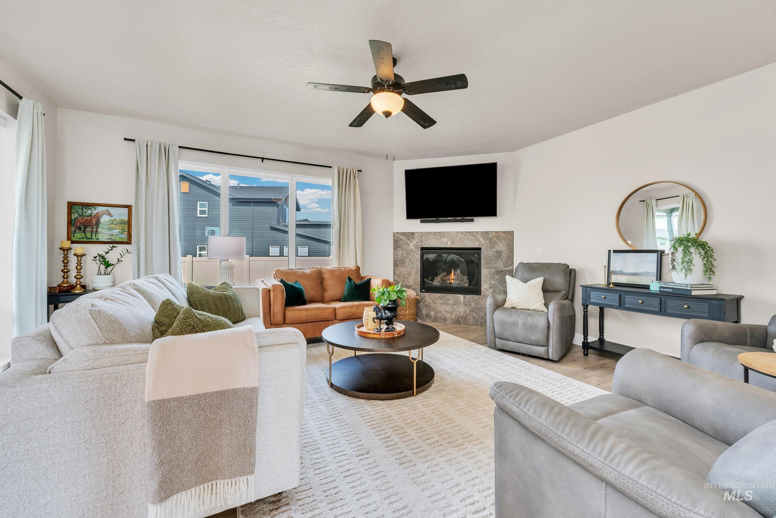 Living area featuring a premium fireplace, a ceiling fan, and wood finished floors