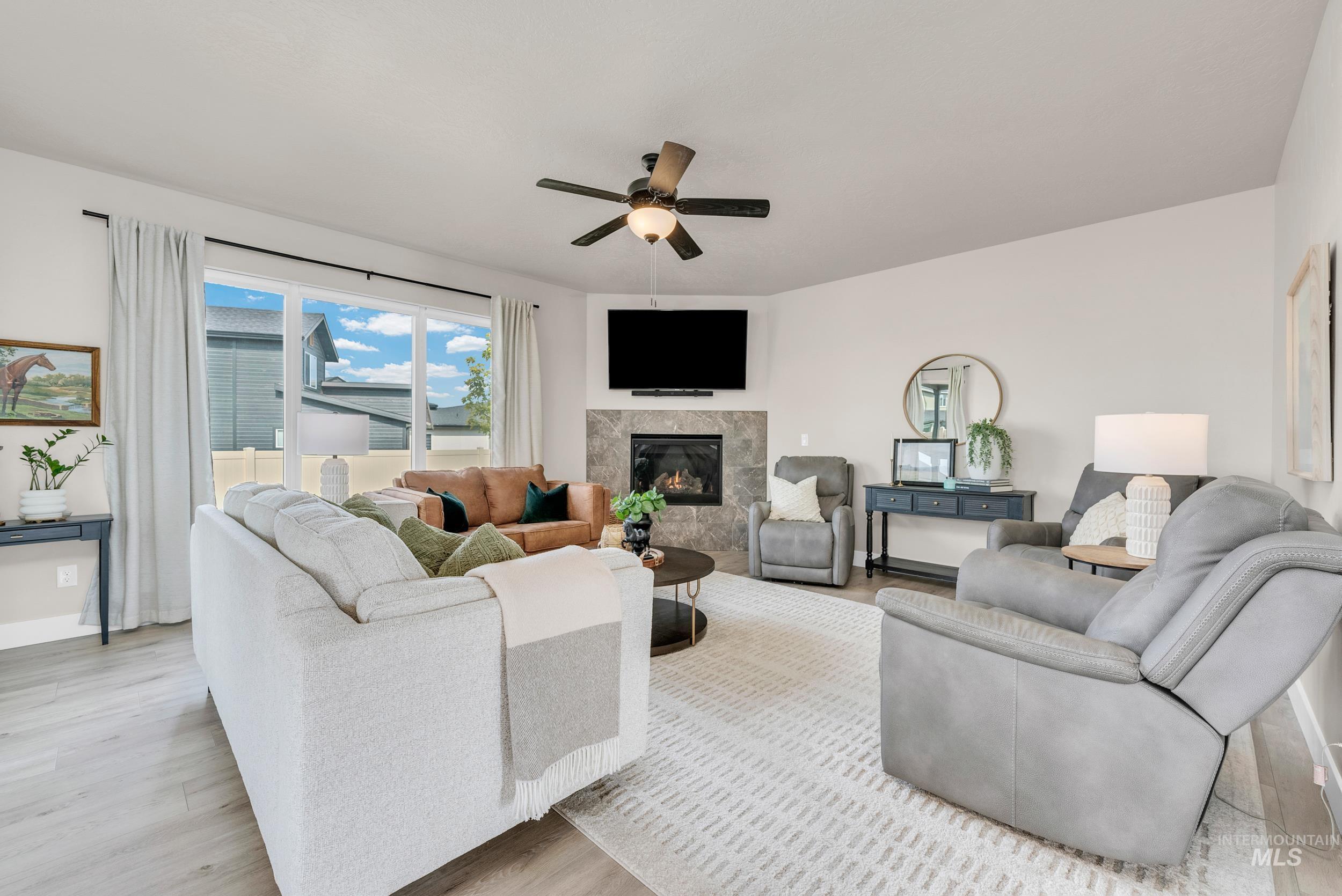 Living area featuring a premium fireplace, light wood-style floors, and a ceiling fan