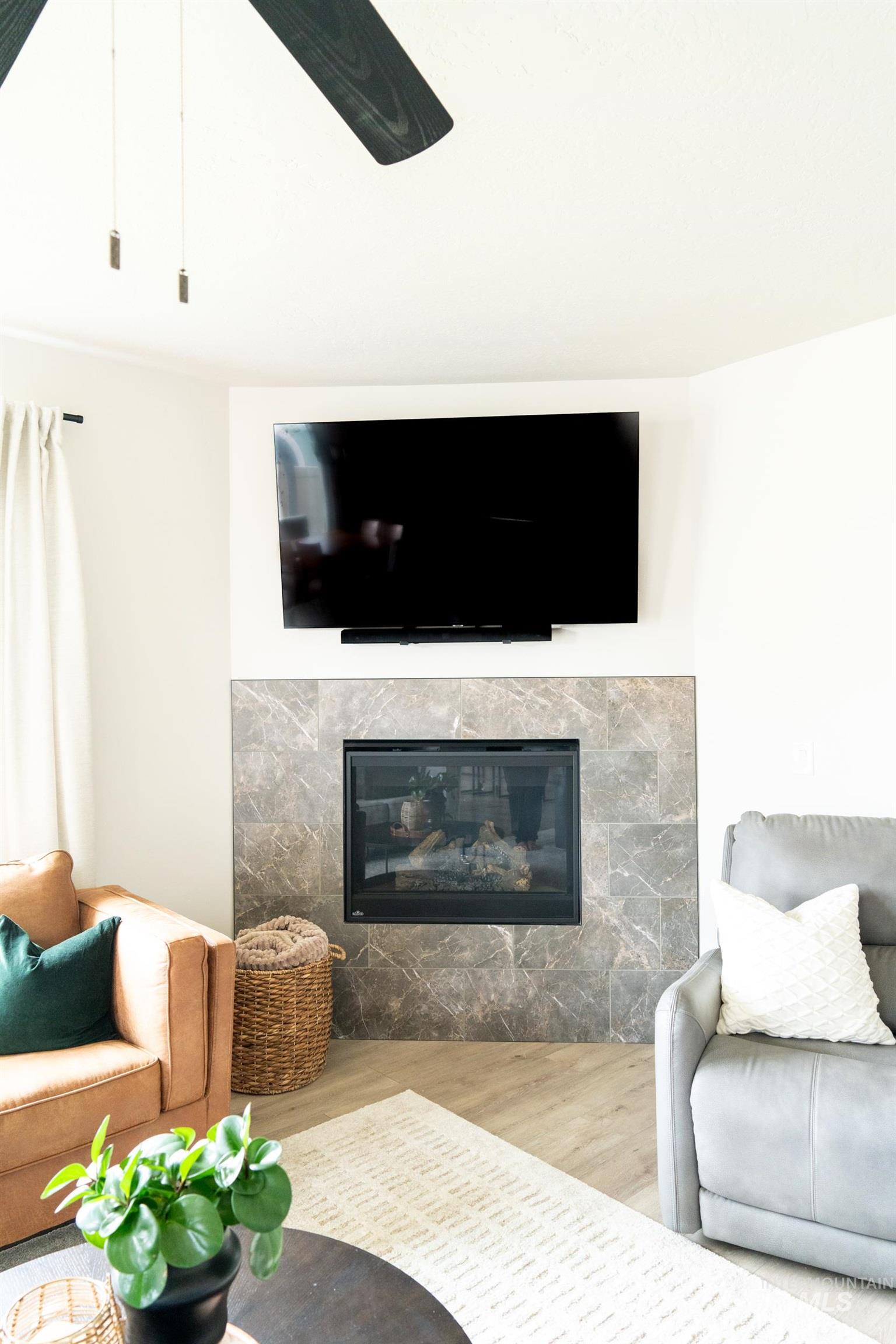 Living room with wood finished floors and a glass covered fireplace