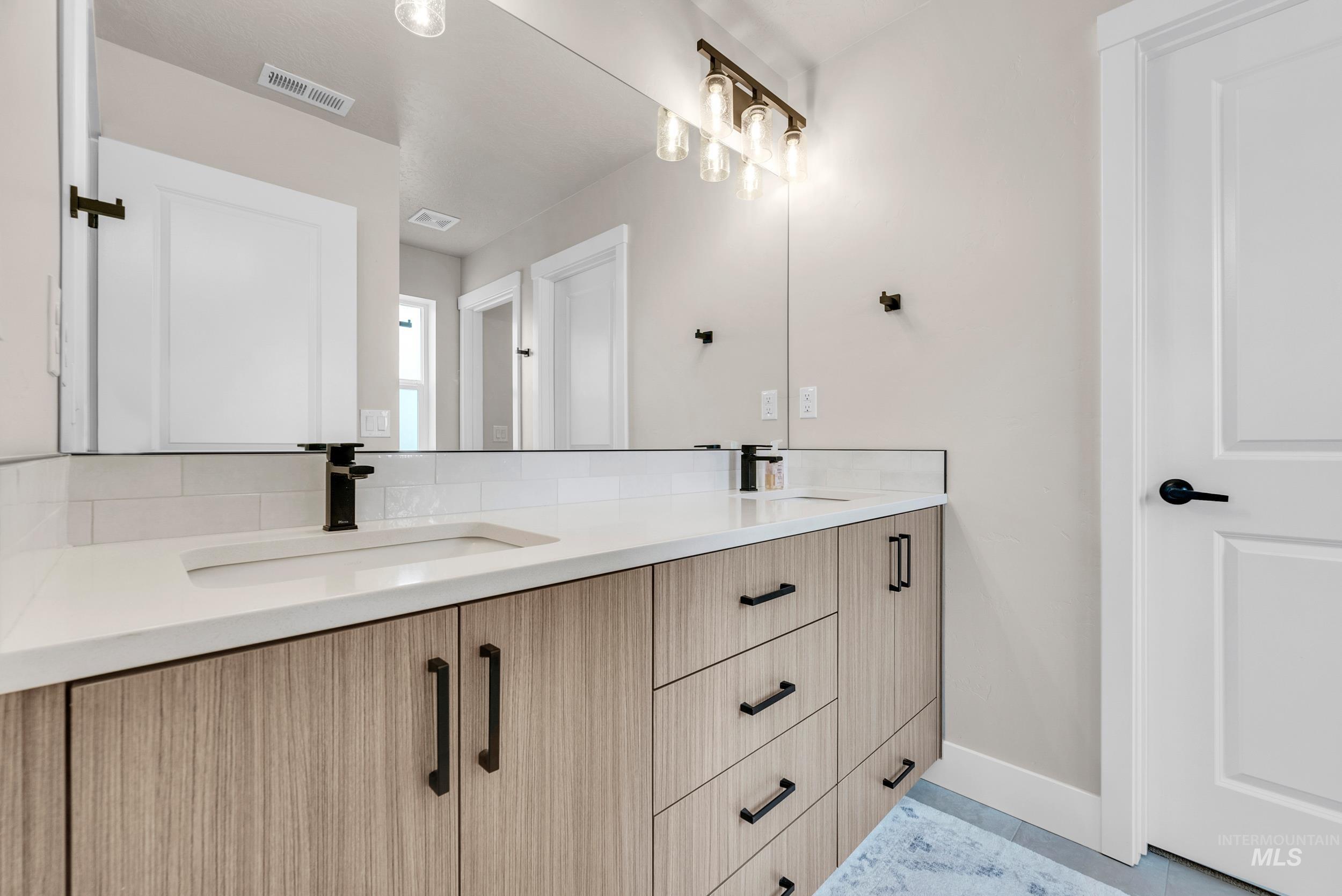 Bathroom with double vanity and light tile patterned floors