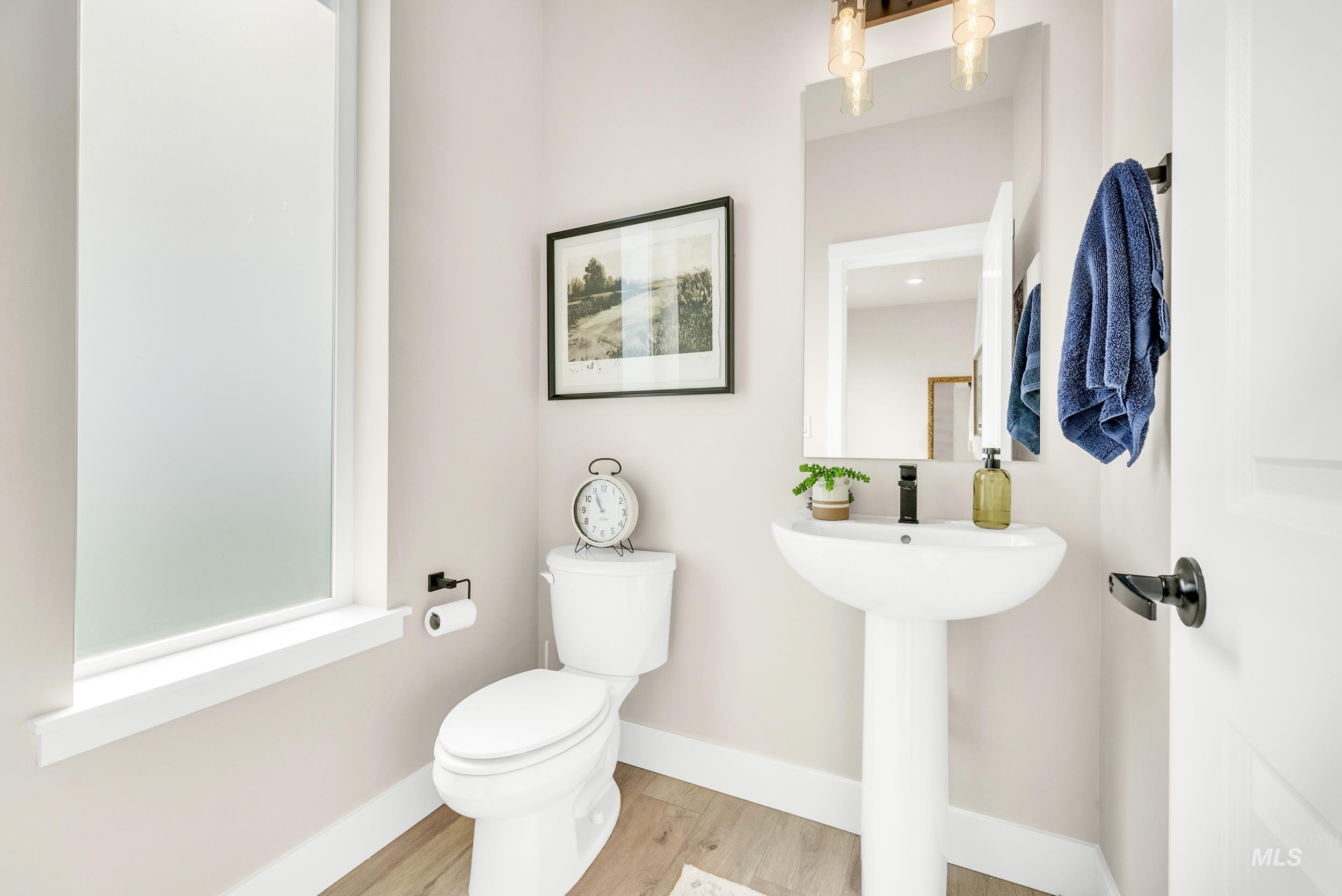 Half bathroom featuring wood finished floors and toilet