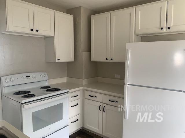 Kitchen with white appliances, light countertops, and white cabinetry