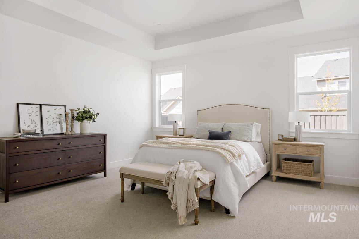 Carpeted bedroom featuring a tray ceiling and baseboards