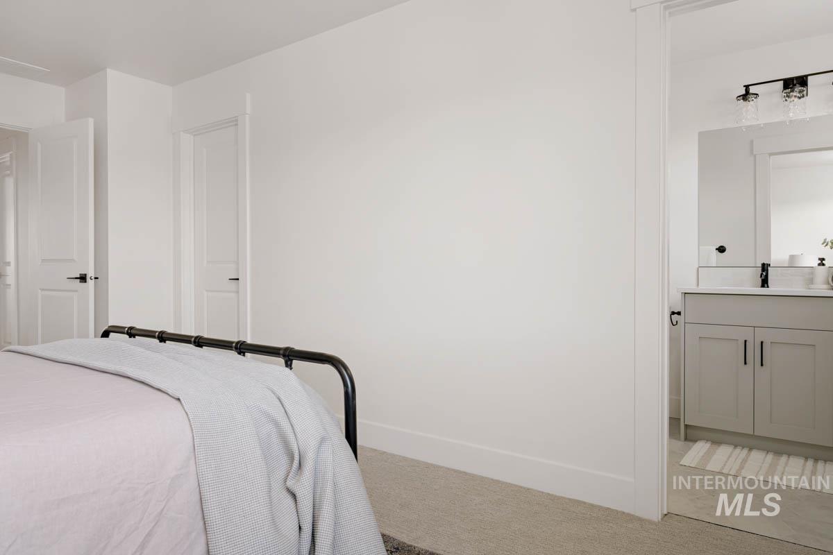 Bedroom featuring light carpet and ensuite bath