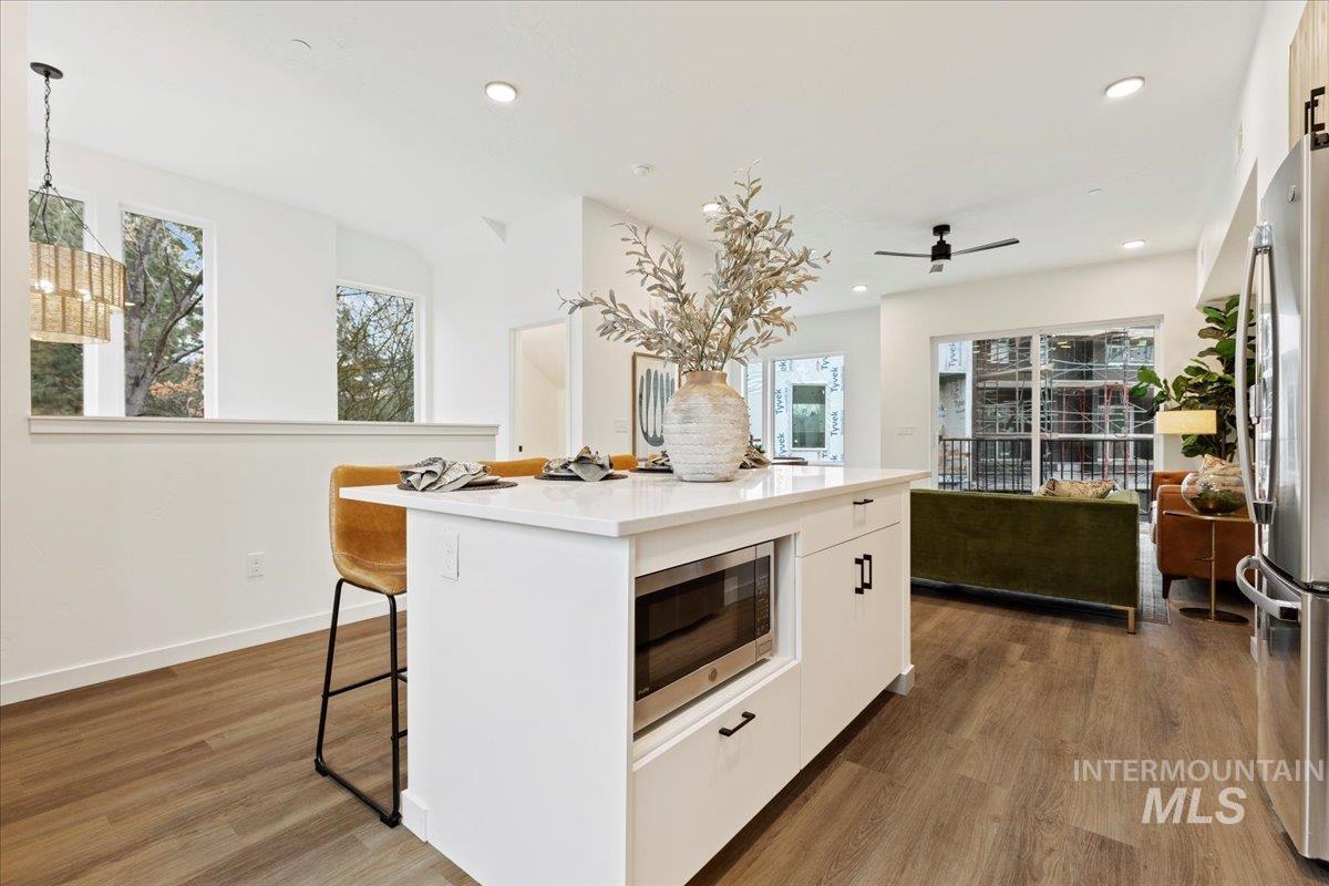 Kitchen with dark wood-style flooring, white cabinetry, stainless steel appliances, a kitchen island, and recessed lighting