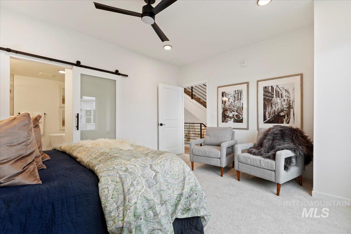 Carpeted bedroom with a barn door, ensuite bath, recessed lighting, and a ceiling fan