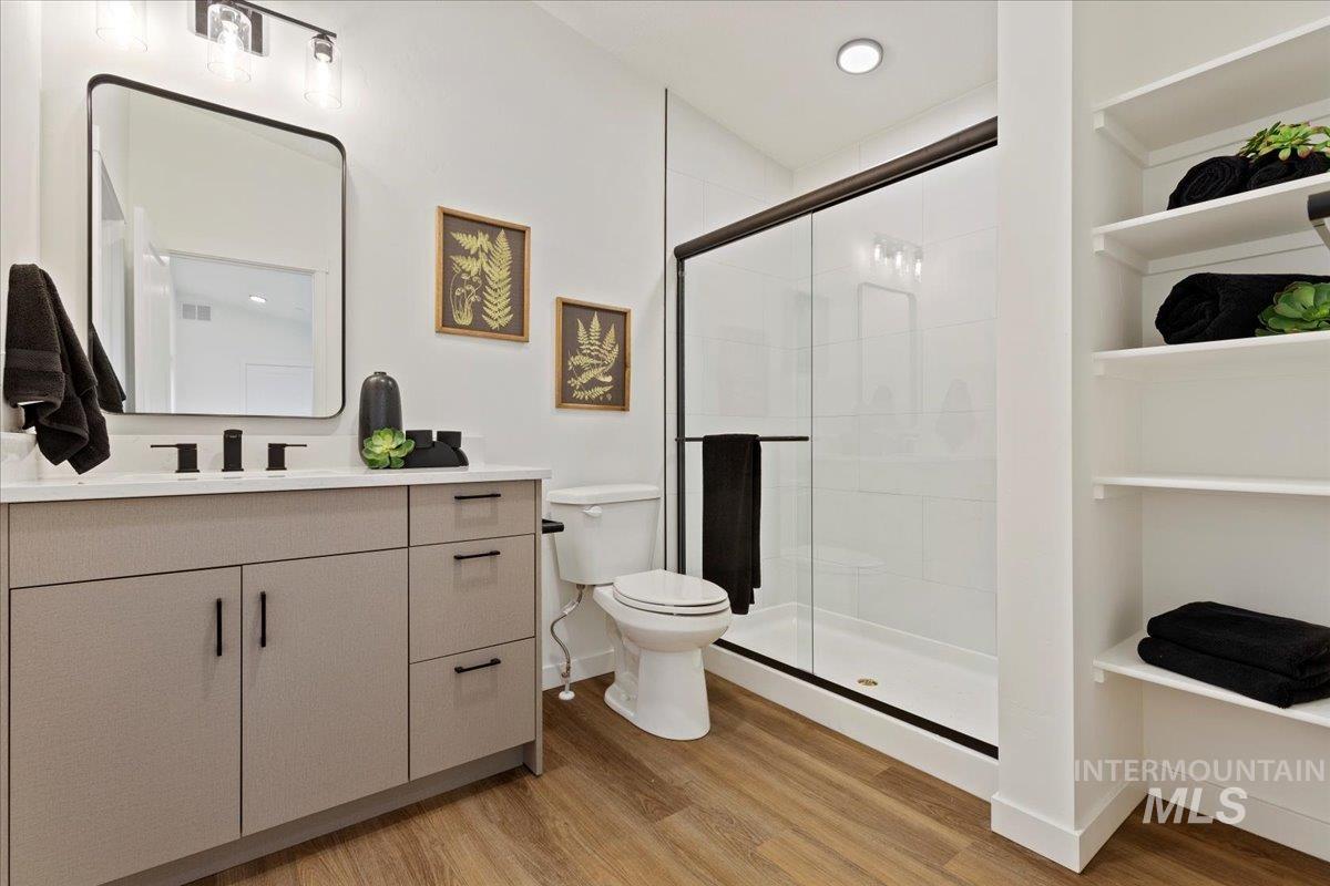 Bathroom featuring light wood-style flooring, a shower stall, vanity, and recessed lighting