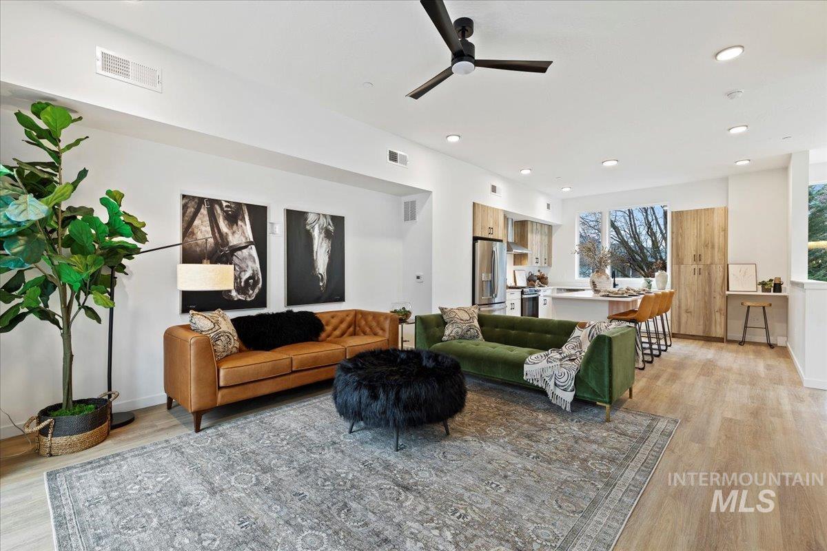 Living room with light wood finished floors, recessed lighting, and a ceiling fan