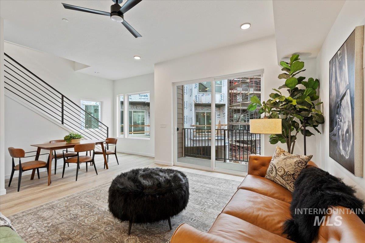 Living area featuring stairs, wood finished floors, a ceiling fan, and recessed lighting