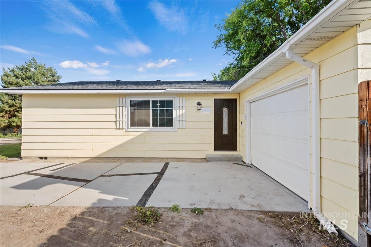 Property entrance featuring a patio, an attached garage, and roof with shingles