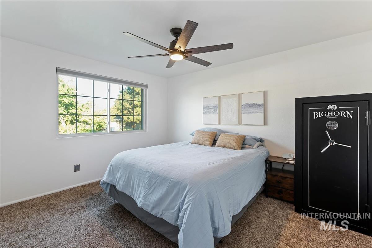 Carpeted bedroom featuring ceiling fan and baseboards