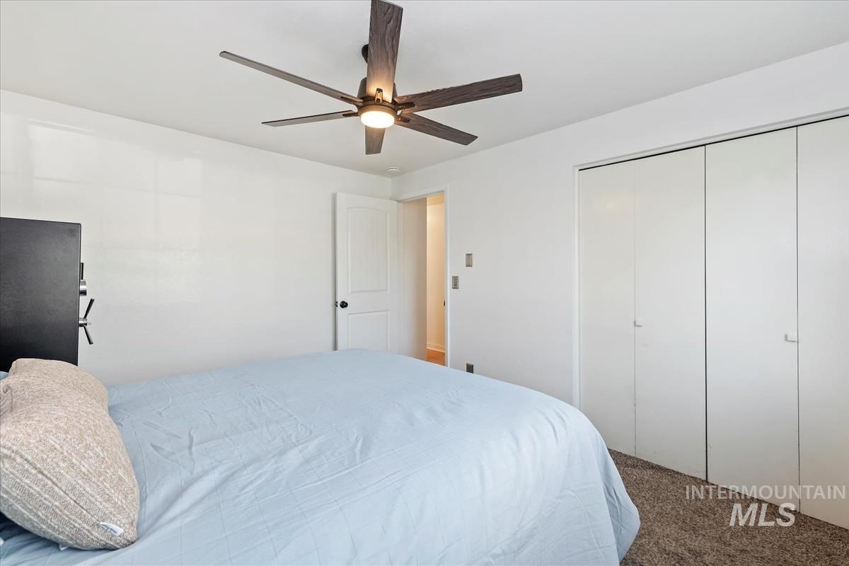 Carpeted bedroom featuring ceiling fan and a closet