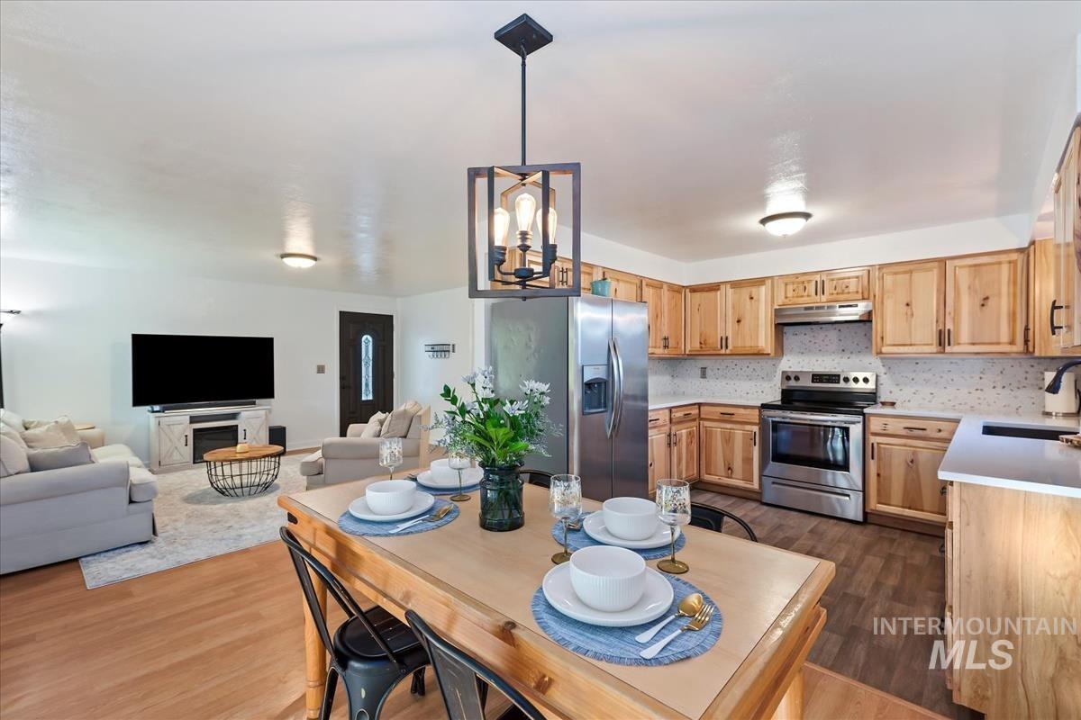 Kitchen with light countertops, stainless steel appliances, backsplash, and dark wood-style flooring