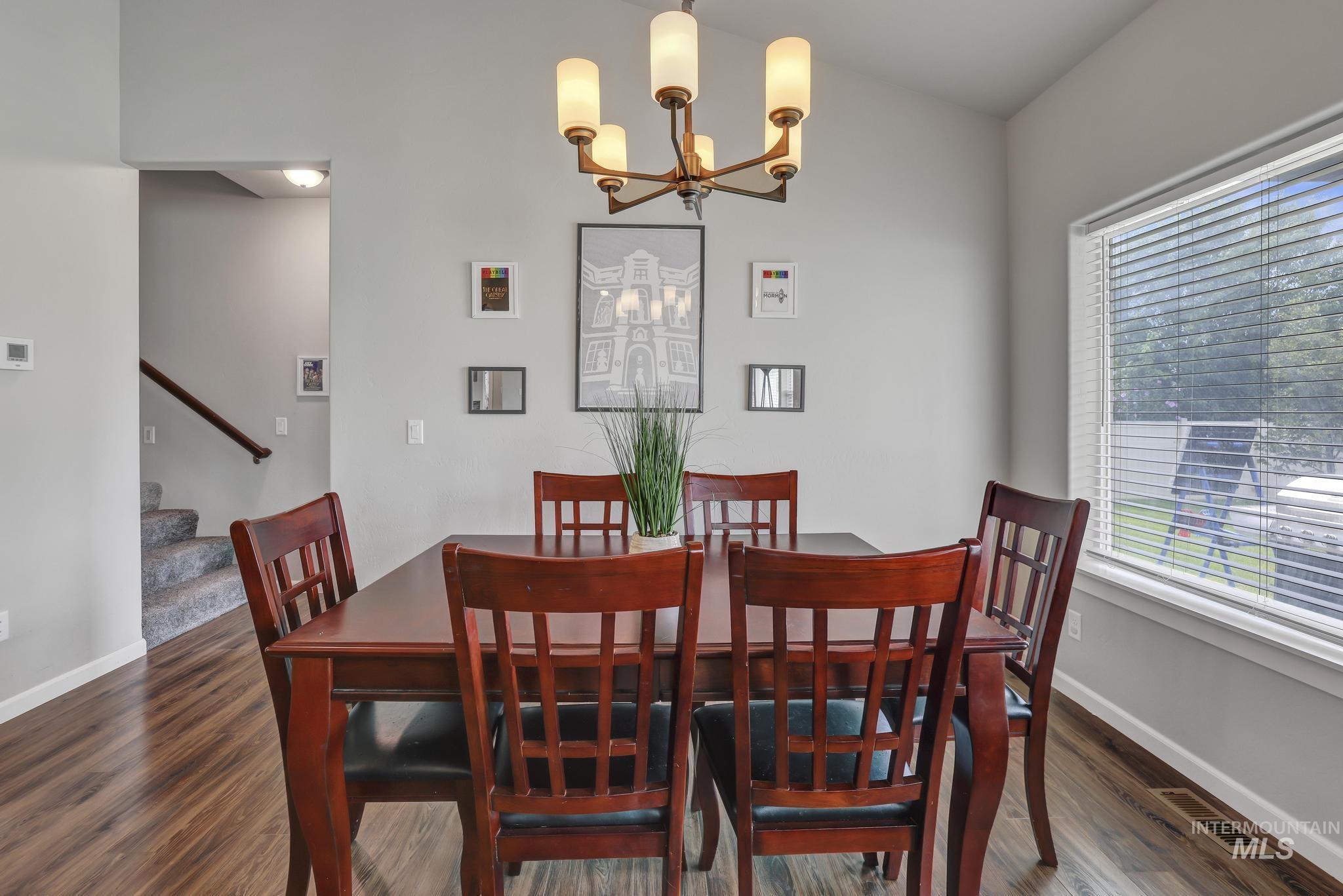 Dining space with a chandelier, stairway, and dark wood finished floors