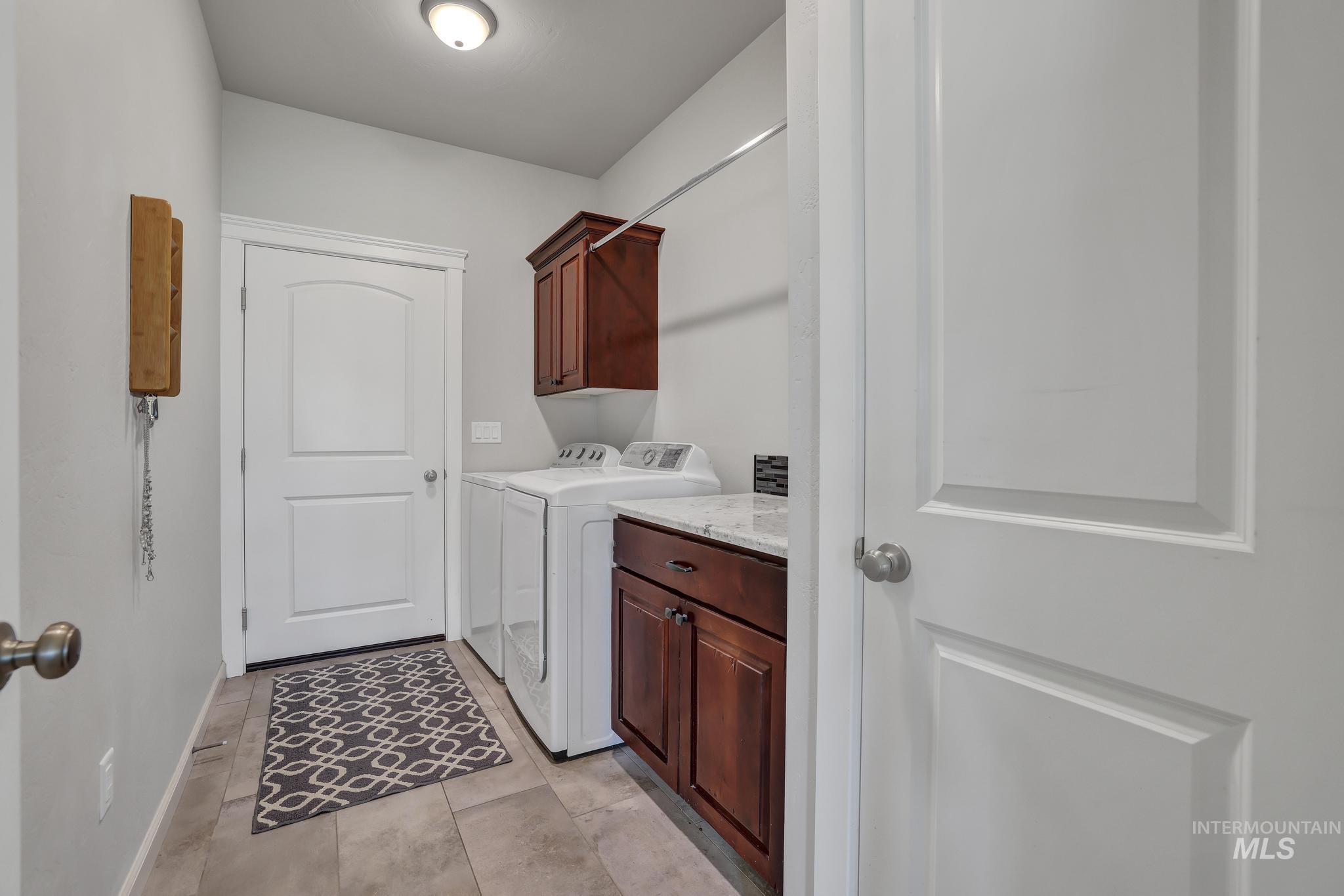 Washroom with cabinet space, independent washer and dryer, and light tile patterned floors