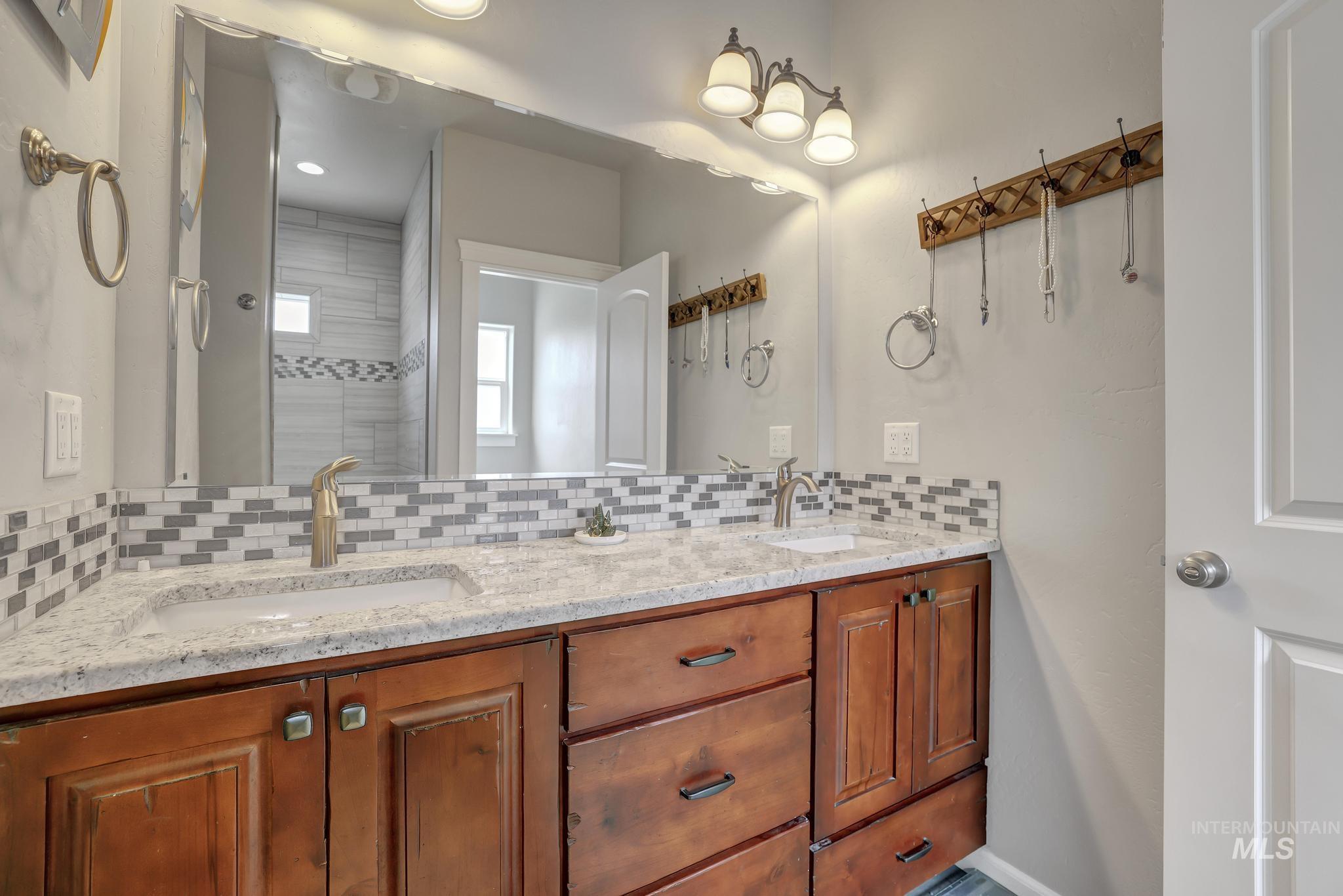 Bathroom with backsplash, double vanity, recessed lighting, and a tile shower