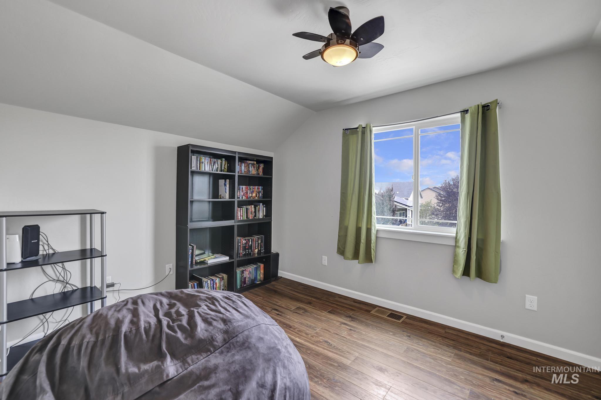 Bedroom featuring dark wood-type flooring, vaulted ceiling, and a ceiling fan