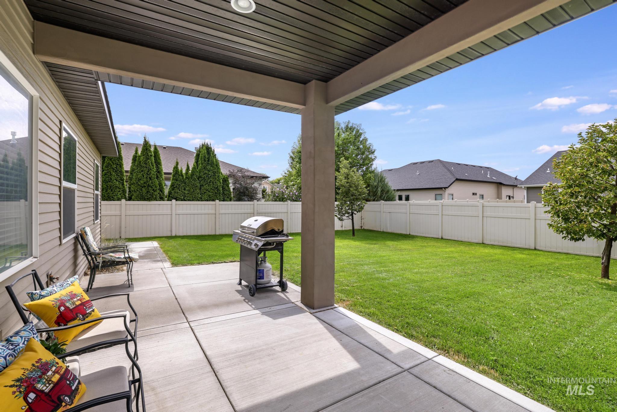 Fenced backyard with a patio area, grilling area, and a residential view