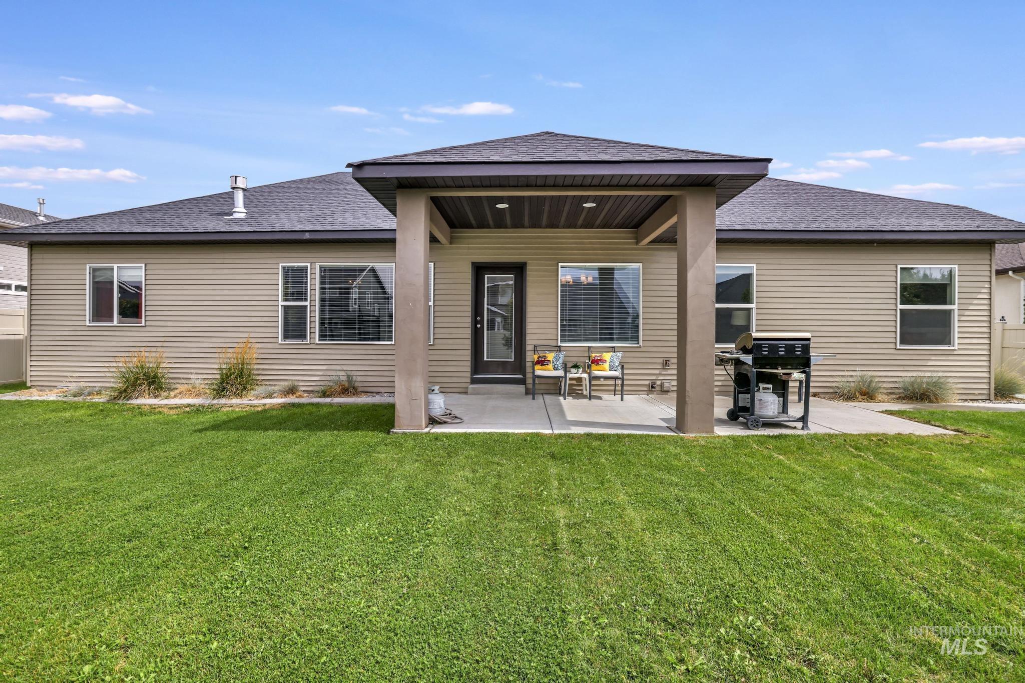 Rear view of house with a shingled roof, a yard, and a patio