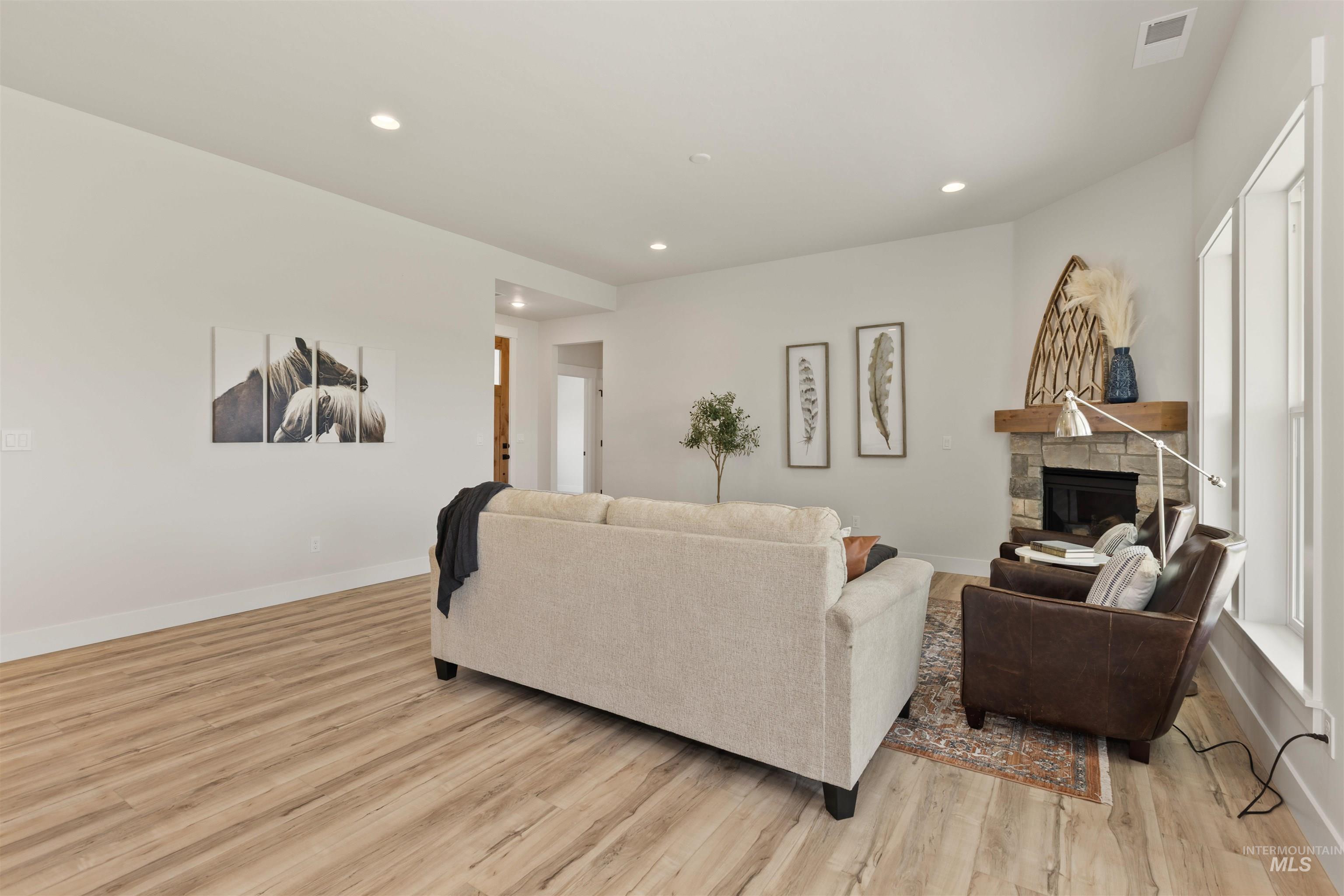 Living area featuring light wood-style flooring, recessed lighting, and a fireplace