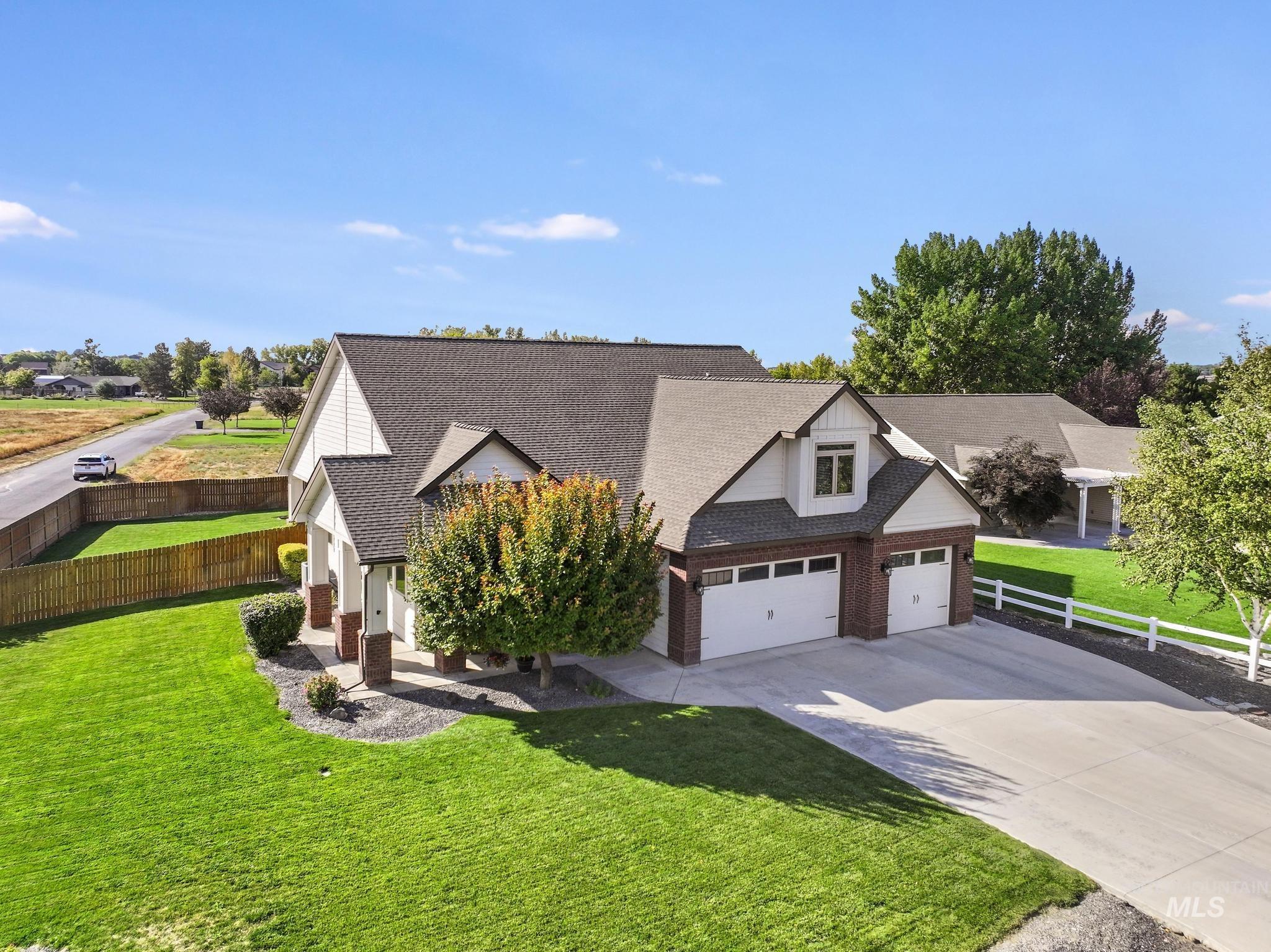 View of front of home with driveway, a shingled roof, and brick siding