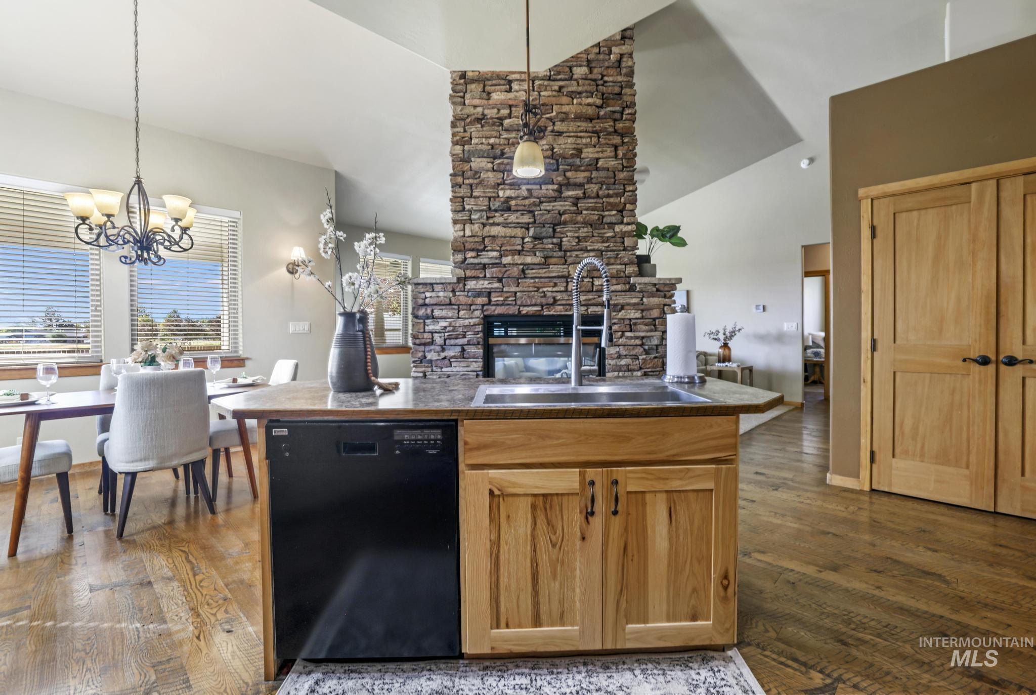 Kitchen featuring dishwasher, dark wood-style flooring, open floor plan, pendant lighting, and high vaulted ceiling