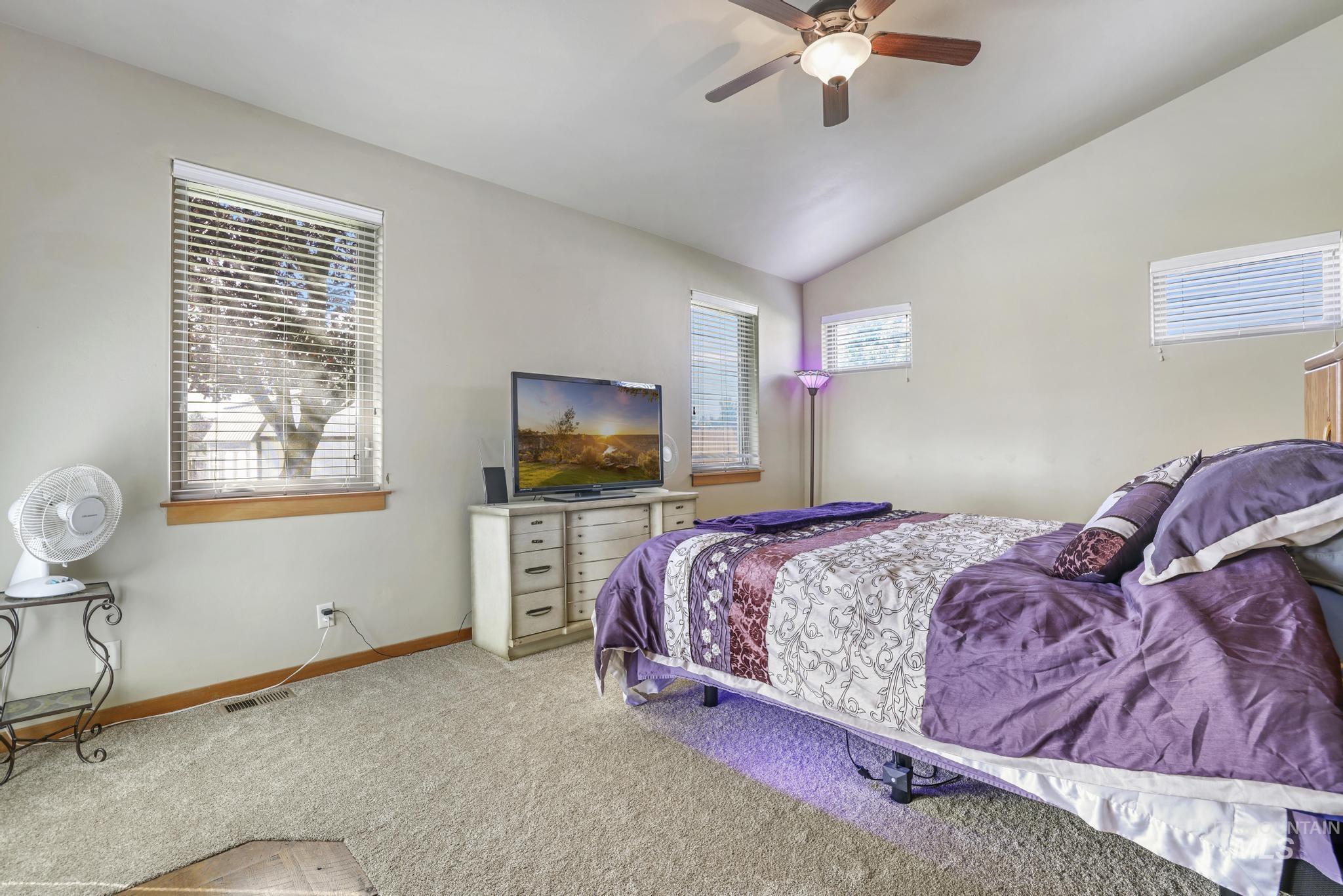 Carpeted bedroom with vaulted ceiling and ceiling fan
