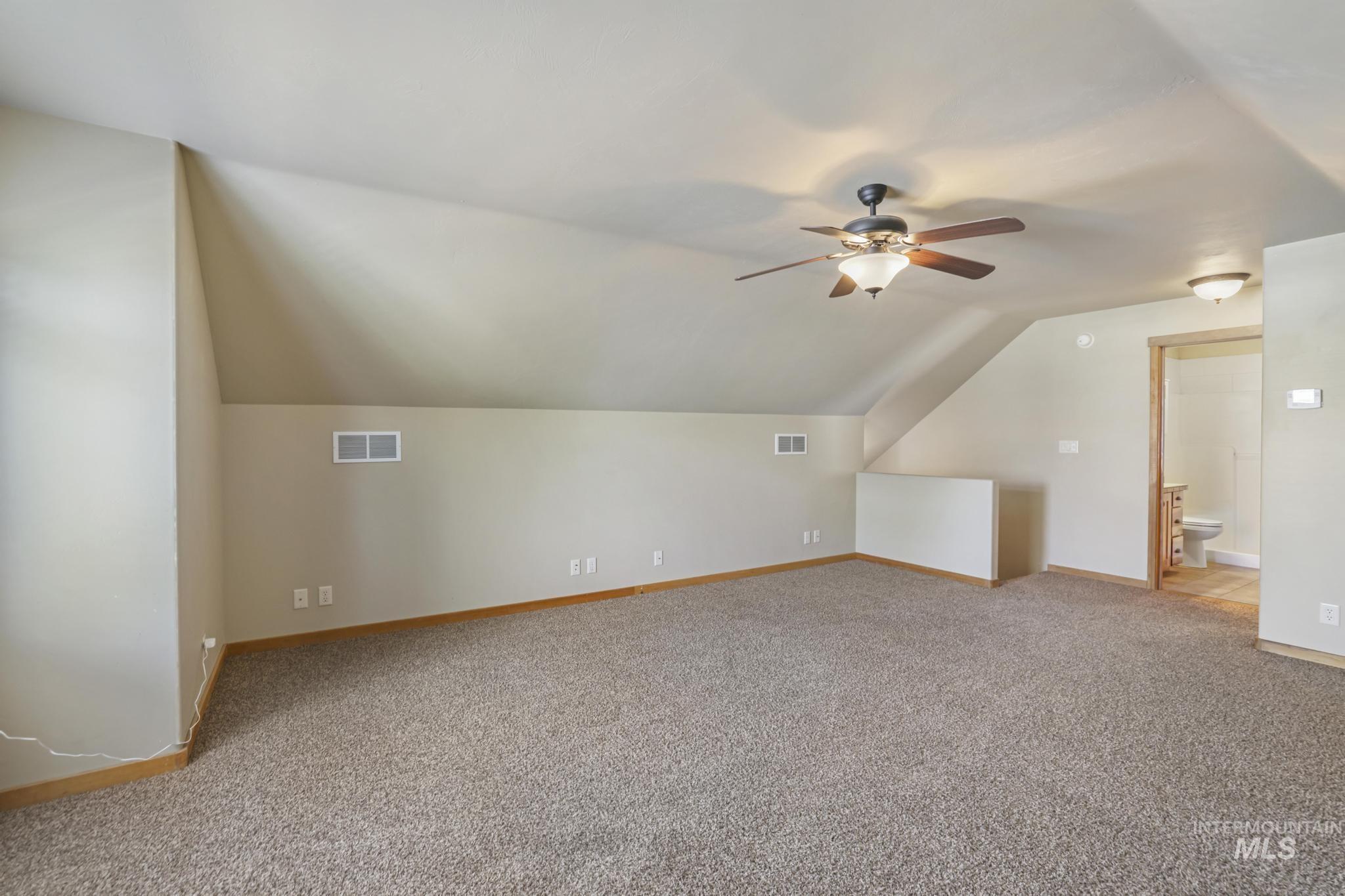 Bonus room with lofted ceiling, light carpet, and a ceiling fan