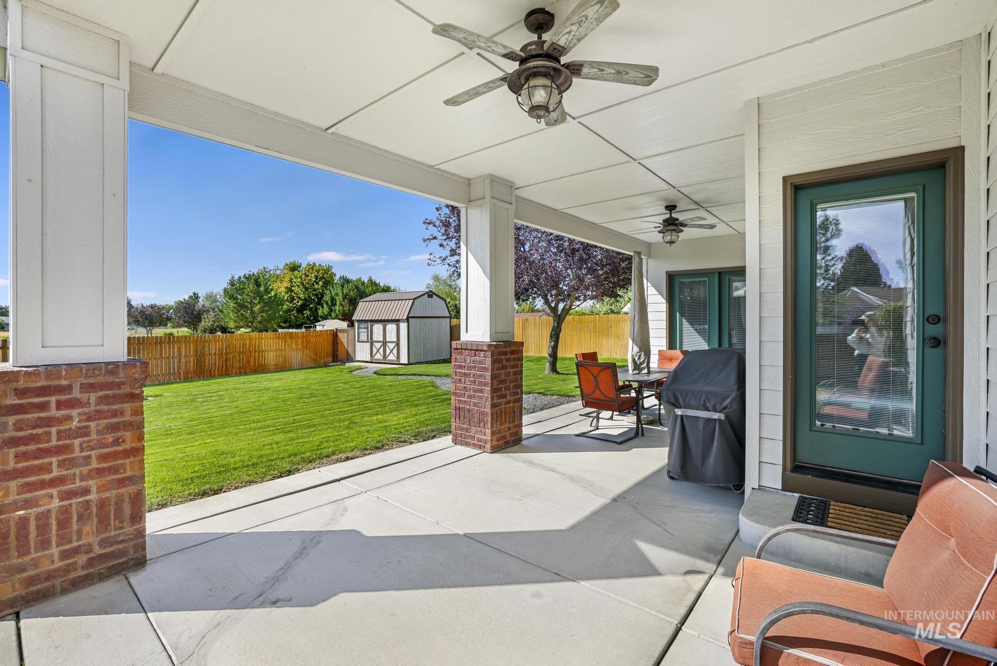 Fenced backyard featuring a patio area, a storage unit, area for grilling, outdoor dining space, and ceiling fan