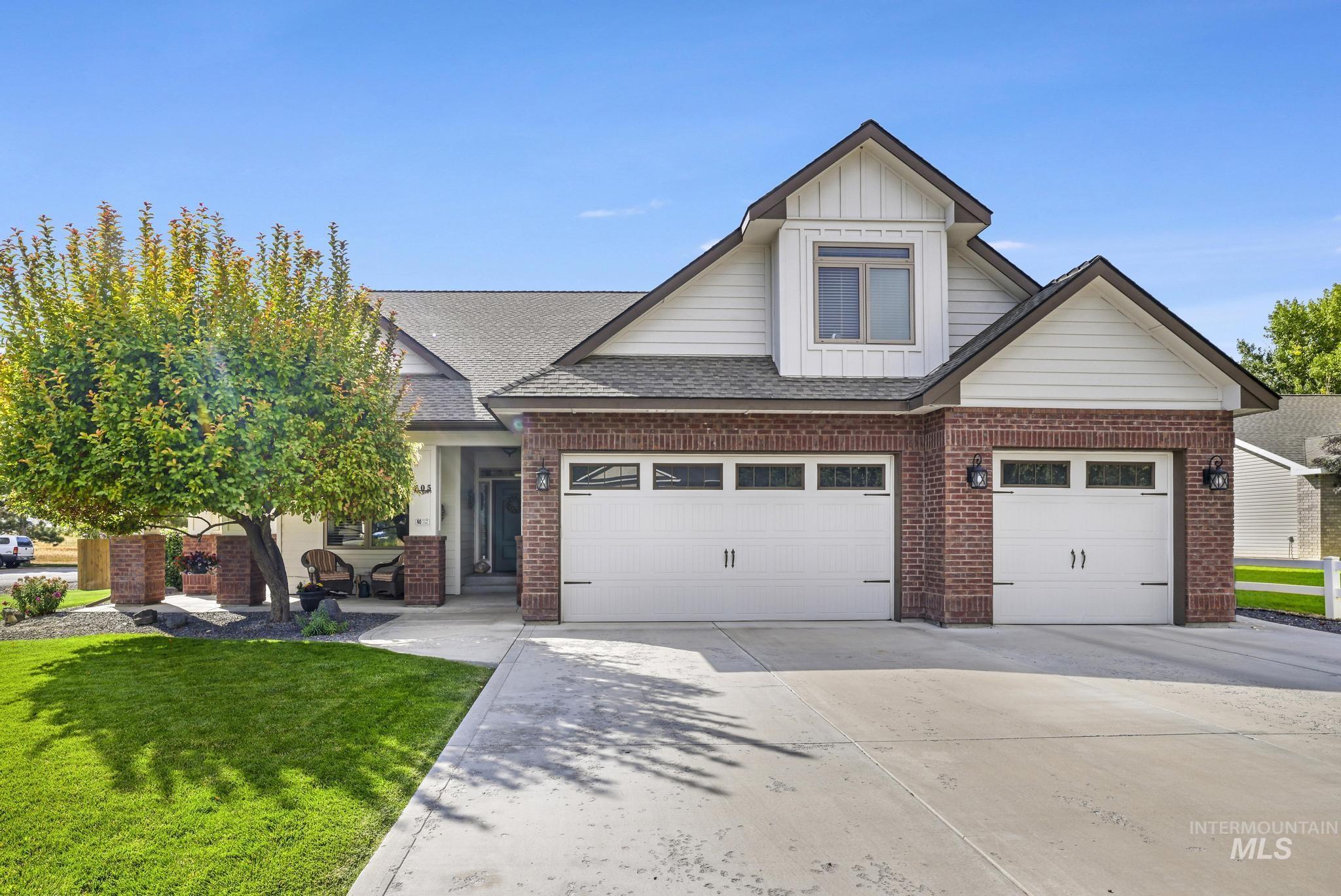 Craftsman inspired home featuring driveway, brick siding, board and batten siding, and a shingled roof