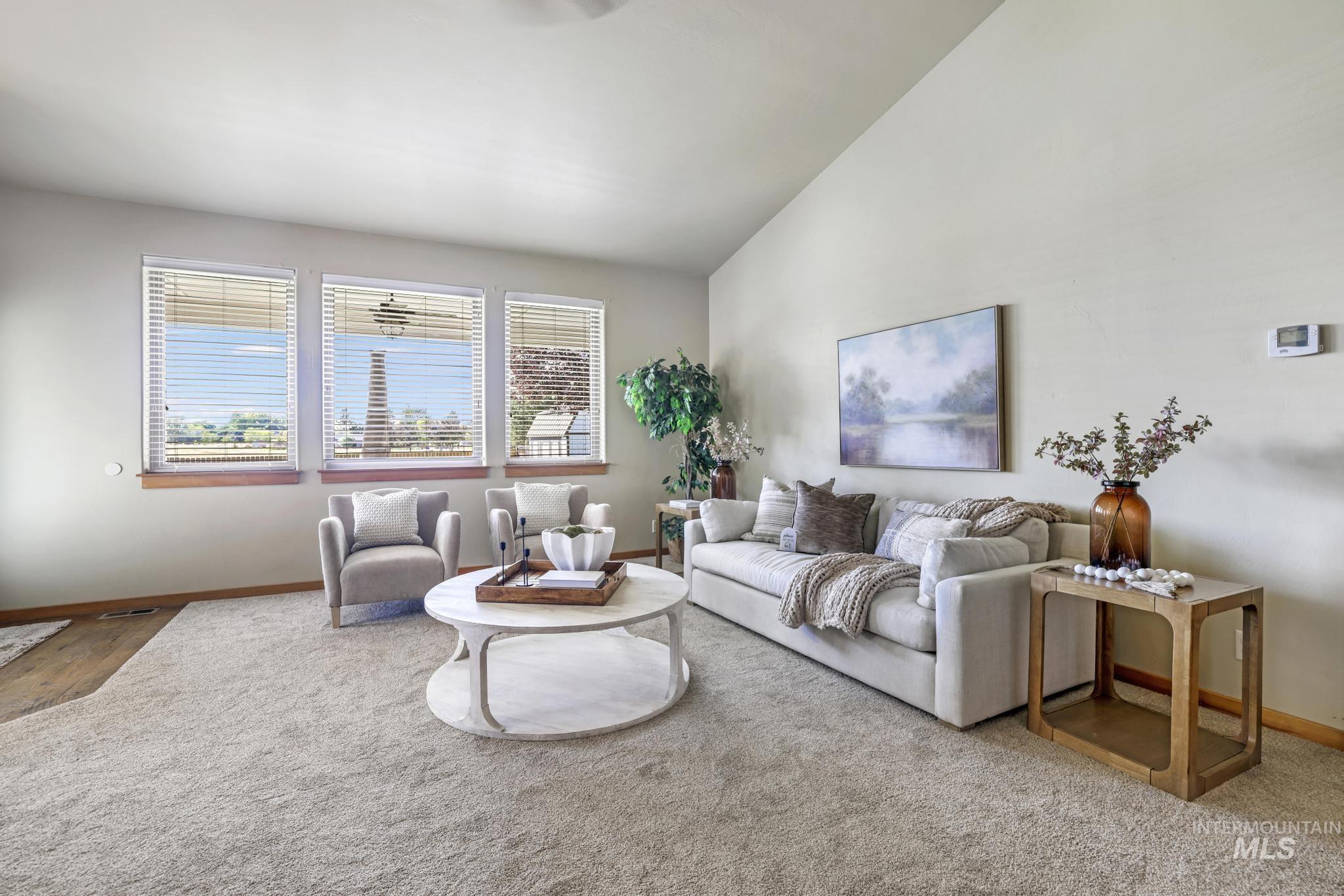 Carpeted living room featuring vaulted ceiling and baseboards