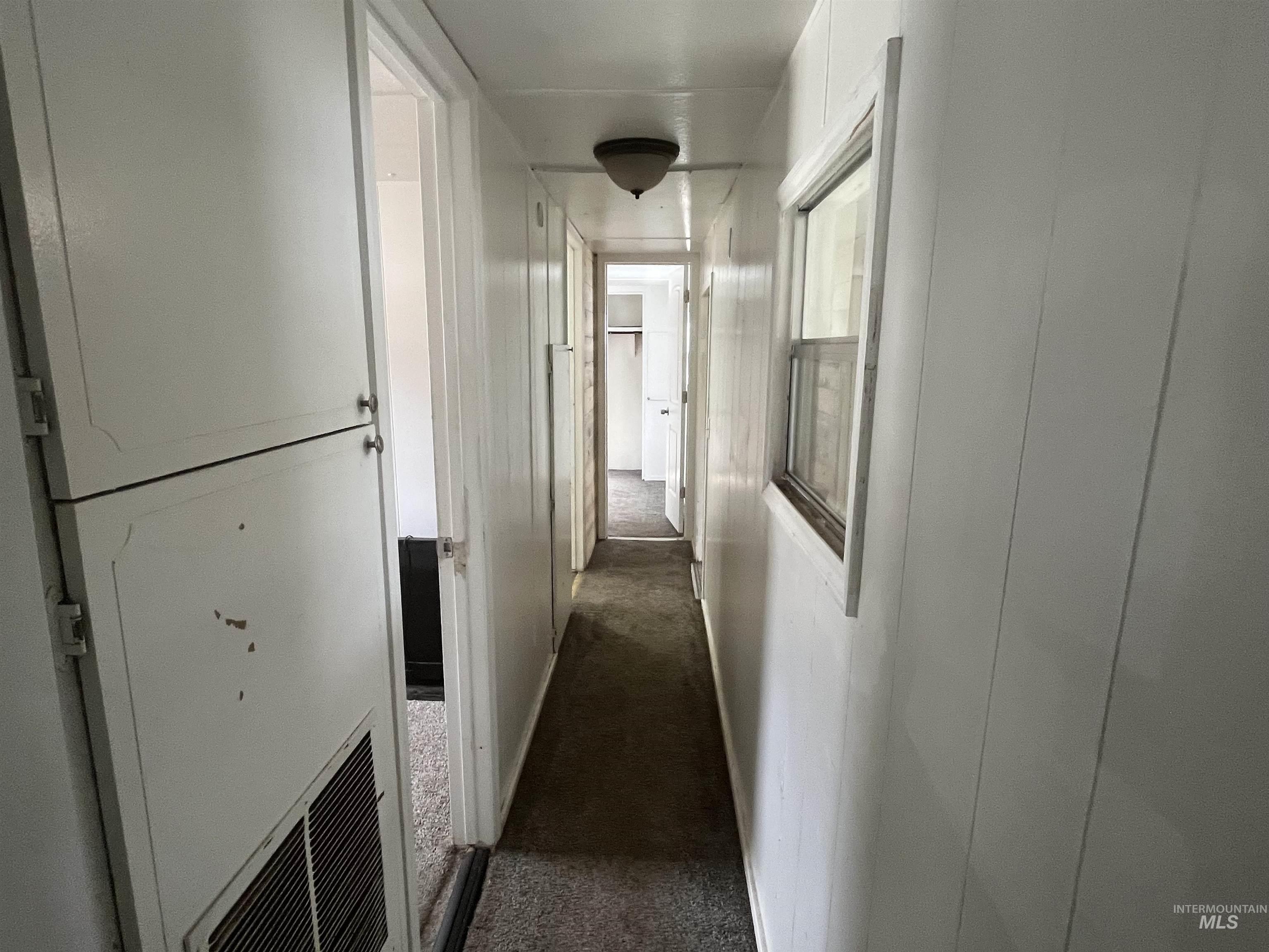 Corridor featuring dark colored carpet