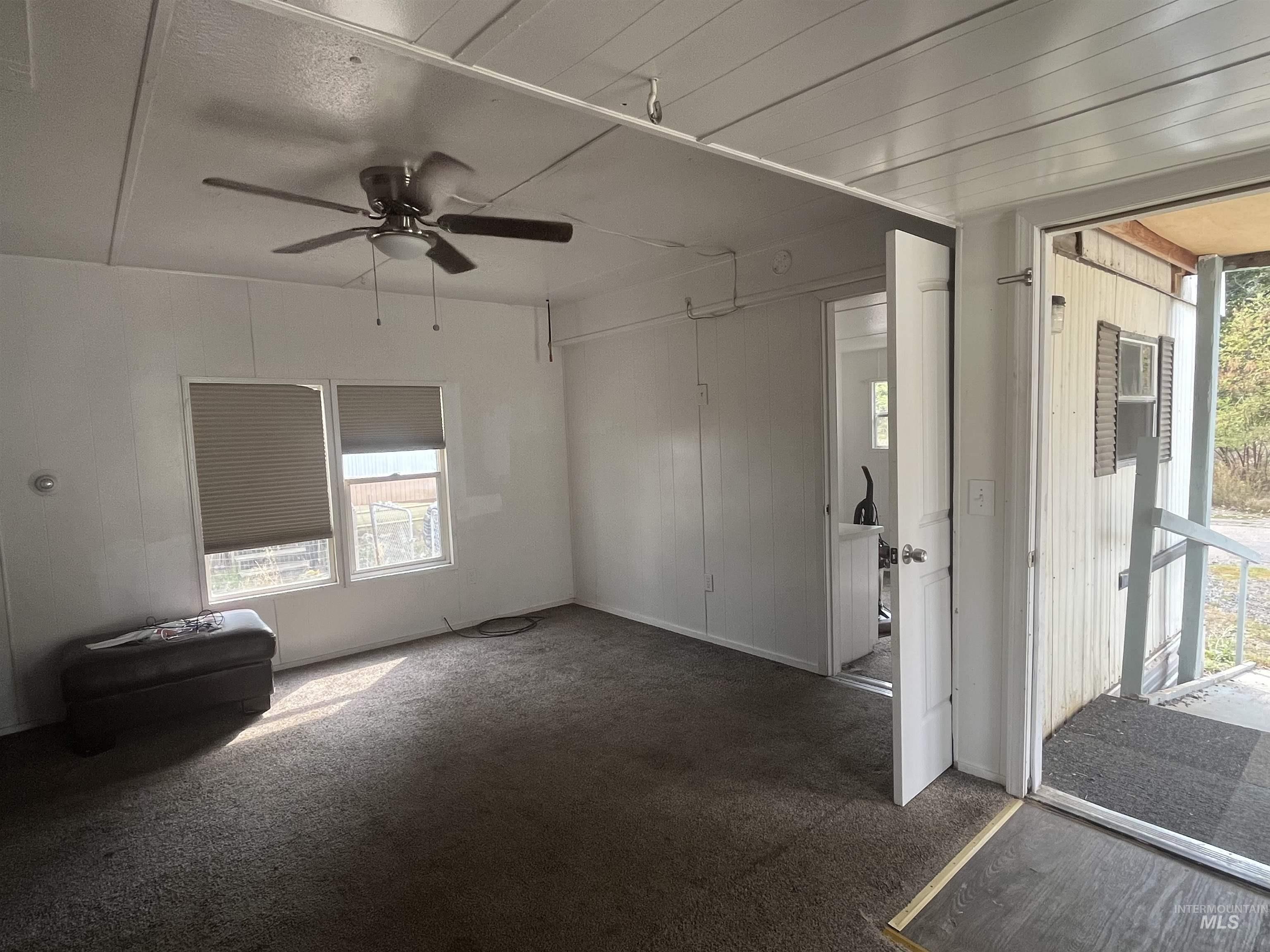 Carpeted spare room featuring a ceiling fan and baseboards