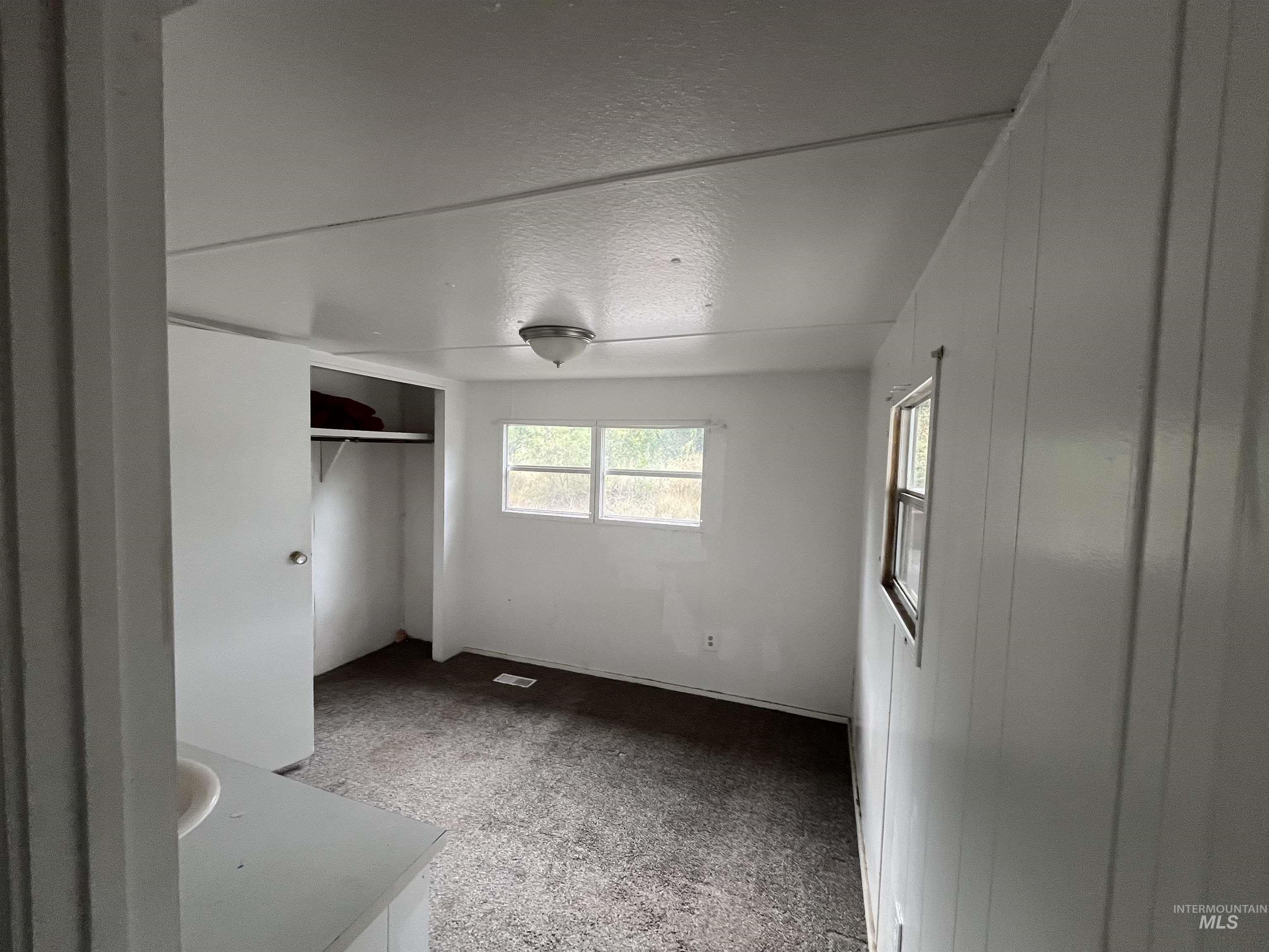 Unfurnished bedroom featuring a textured ceiling, a closet, and light colored carpet