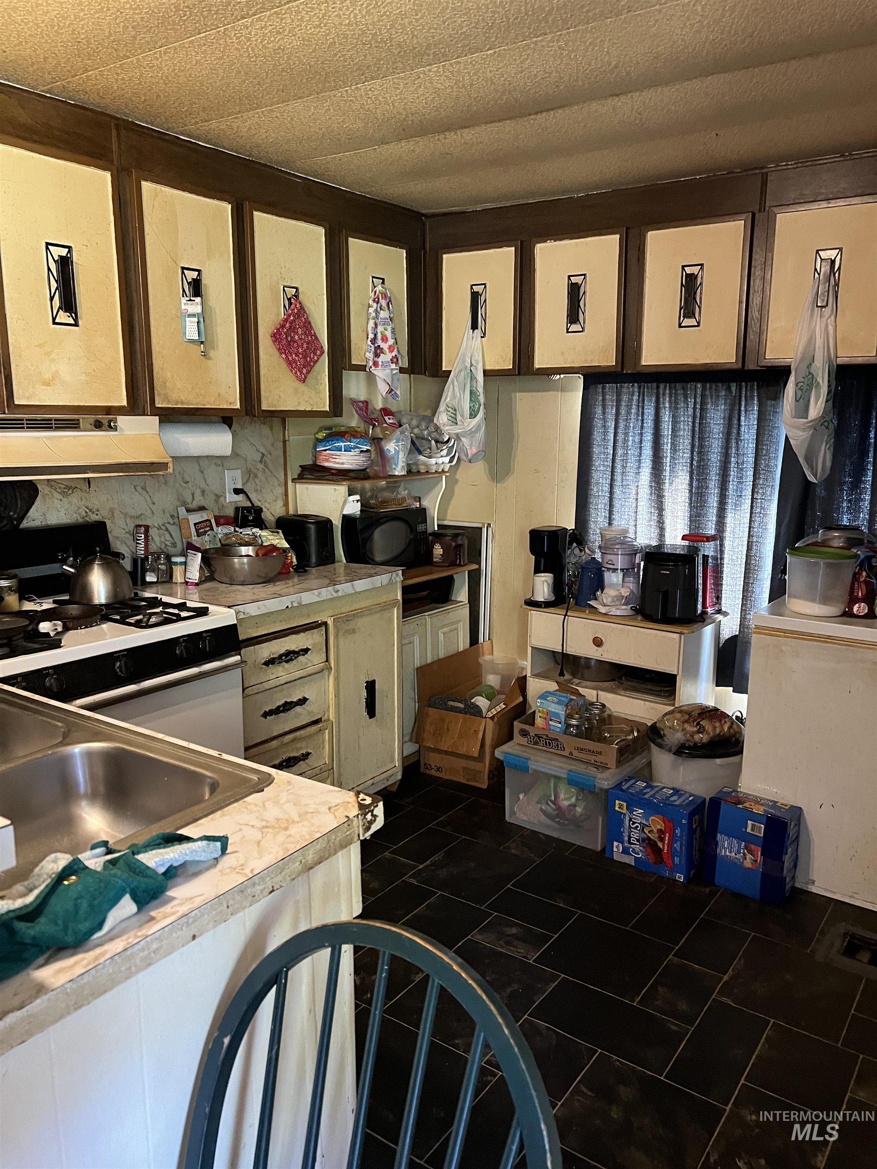 Kitchen with white gas stove, light countertops, and extractor fan