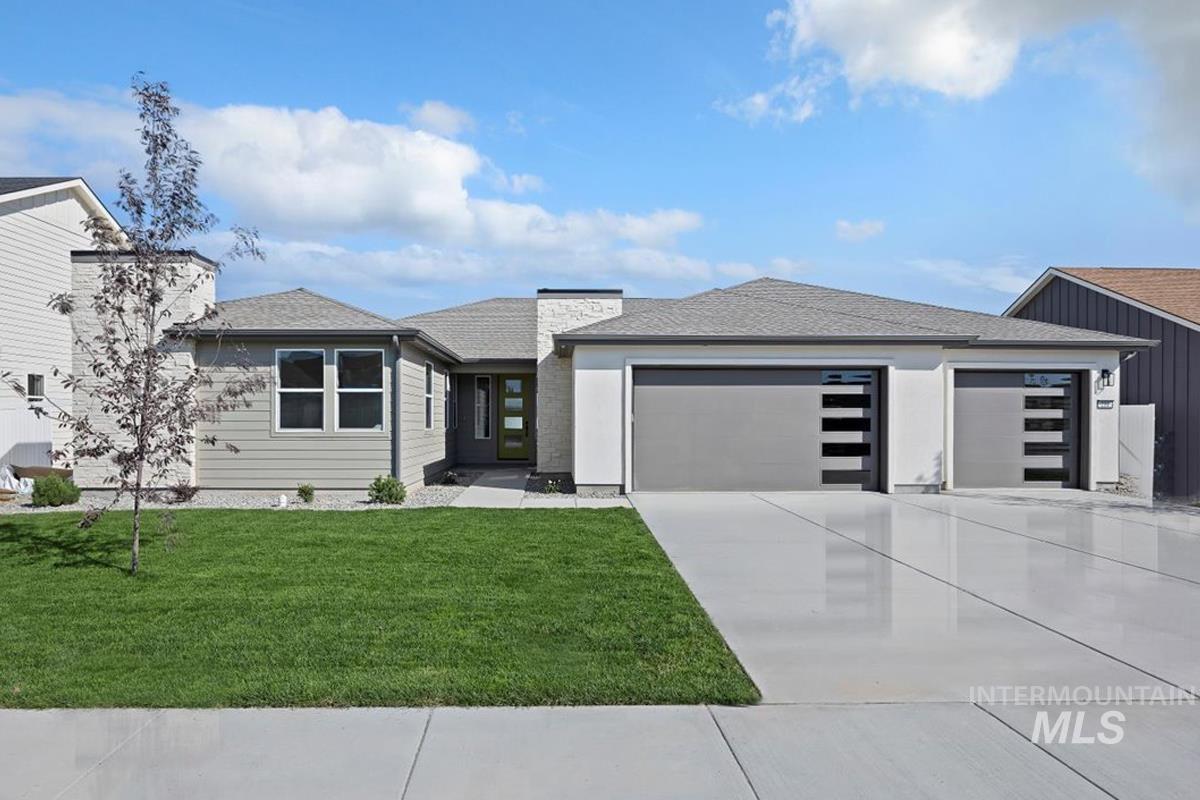 View of front of property featuring a garage, roof with shingles, driveway, and a front lawn