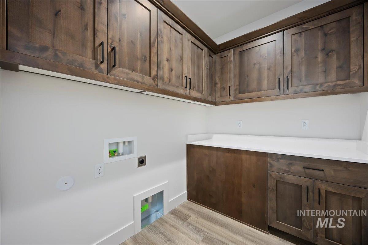 Laundry area featuring light wood-type flooring, washer hookup, and cabinet space
