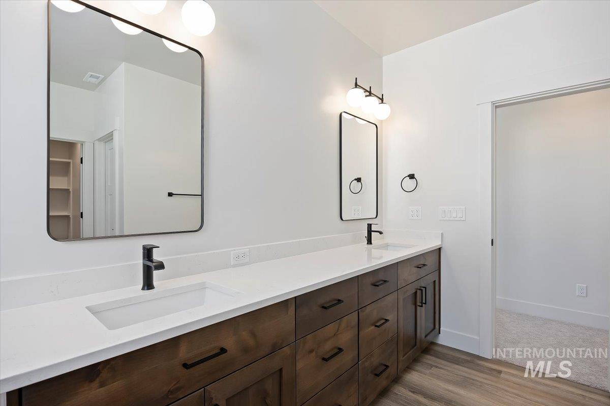 Bathroom with double vanity and light wood-type flooring