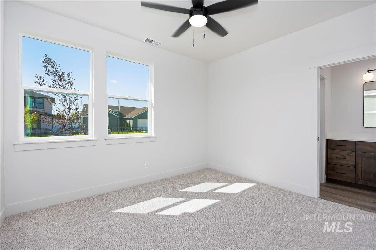 Spare room featuring carpet, plenty of natural light, and a ceiling fan